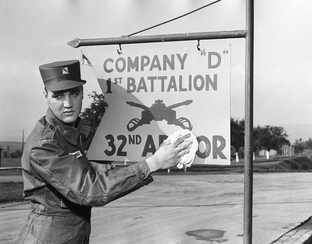 Elvis Presley in U.S. Army uniform cleaning a sign for Company D