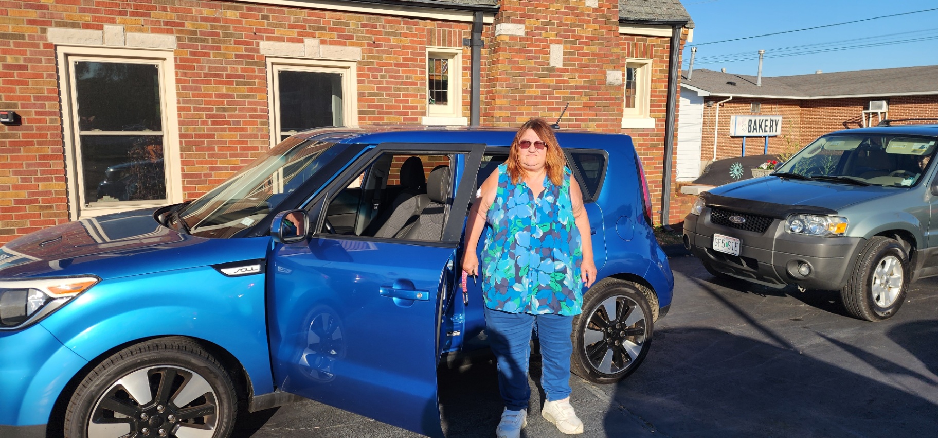 Customer standing next to blue Kia Soul