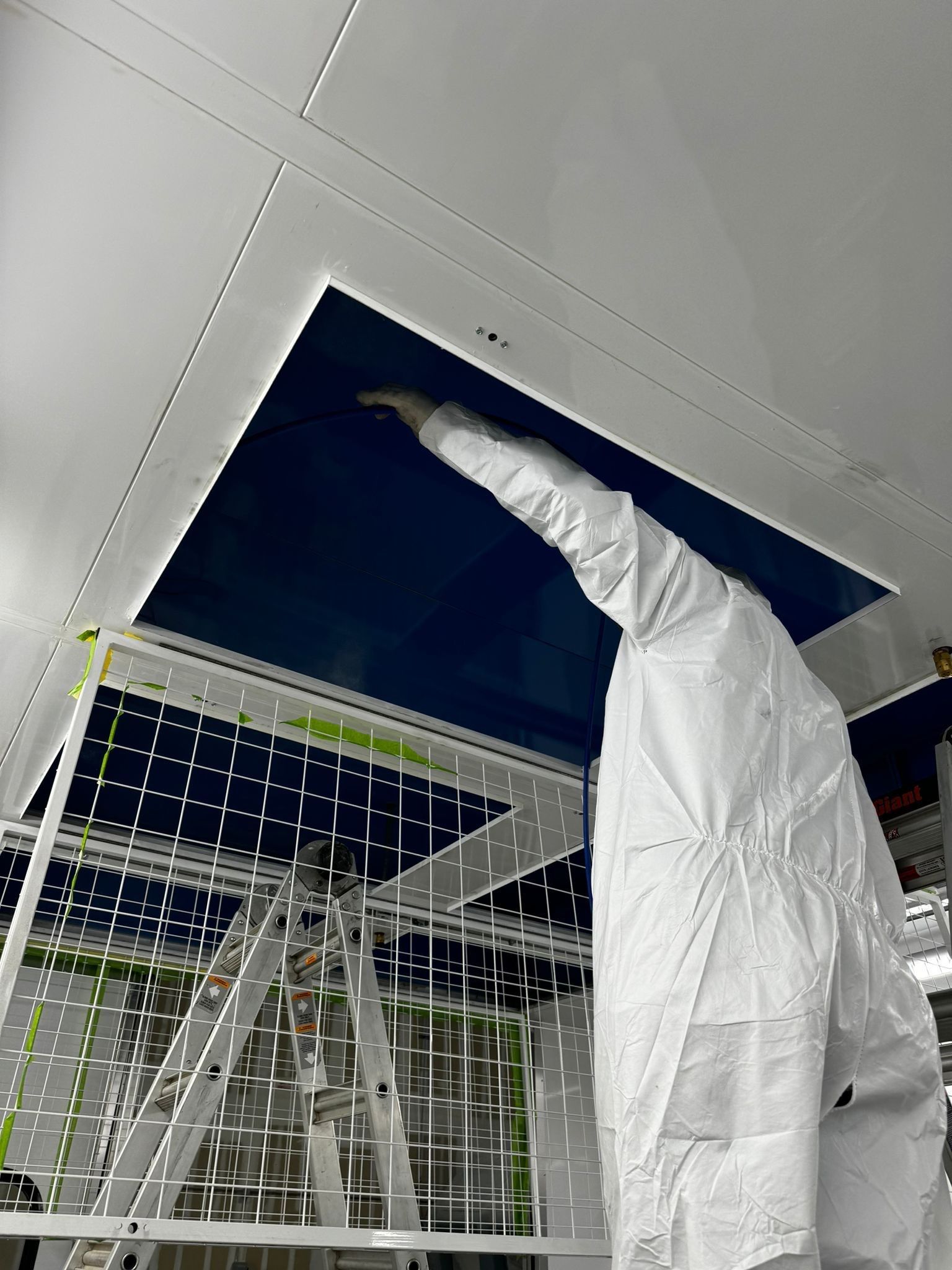 Technician in a protective suit accessing an air duct opening in the ceiling