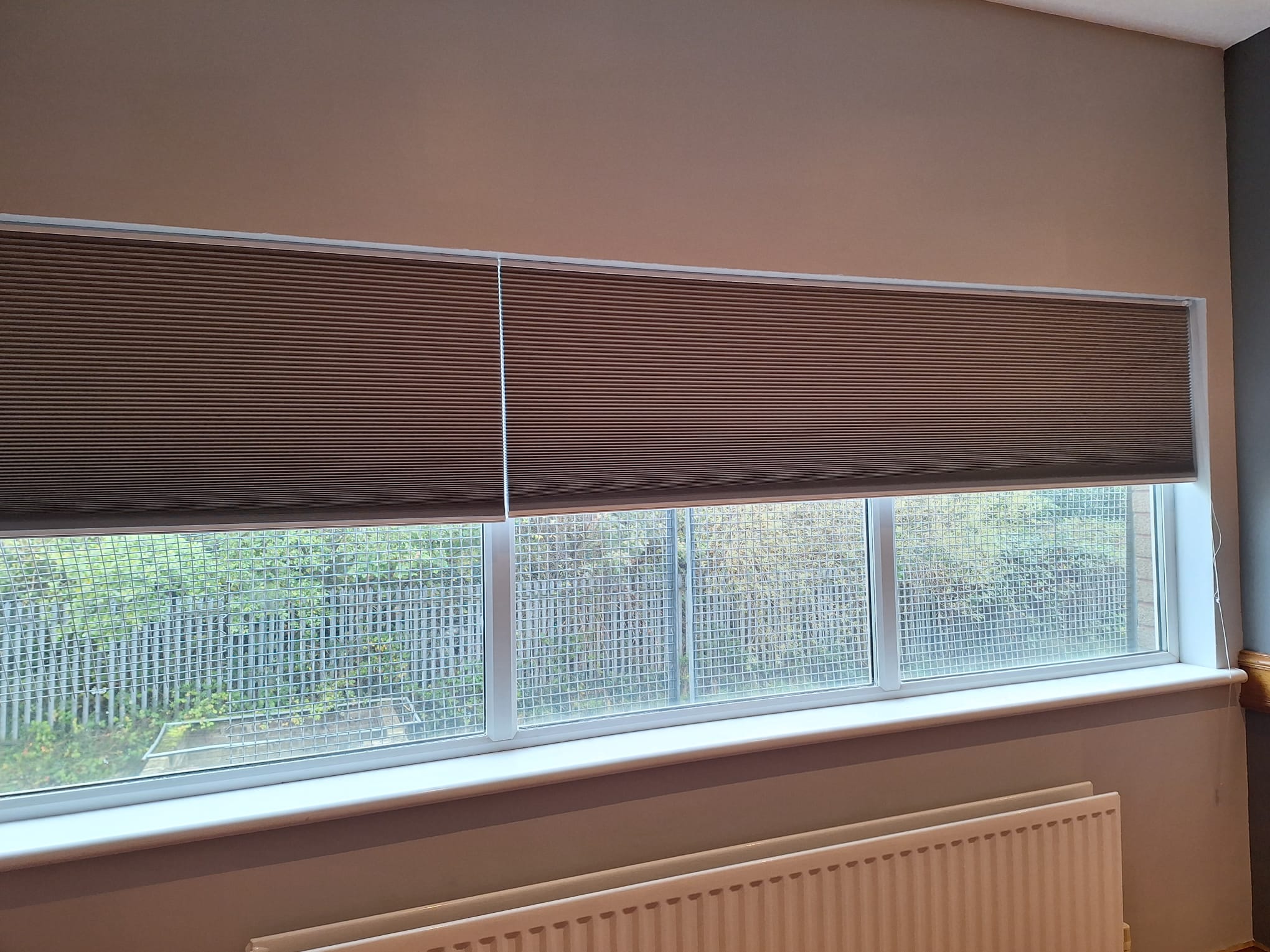 Bespoke pleated blinds installed on a wide double window