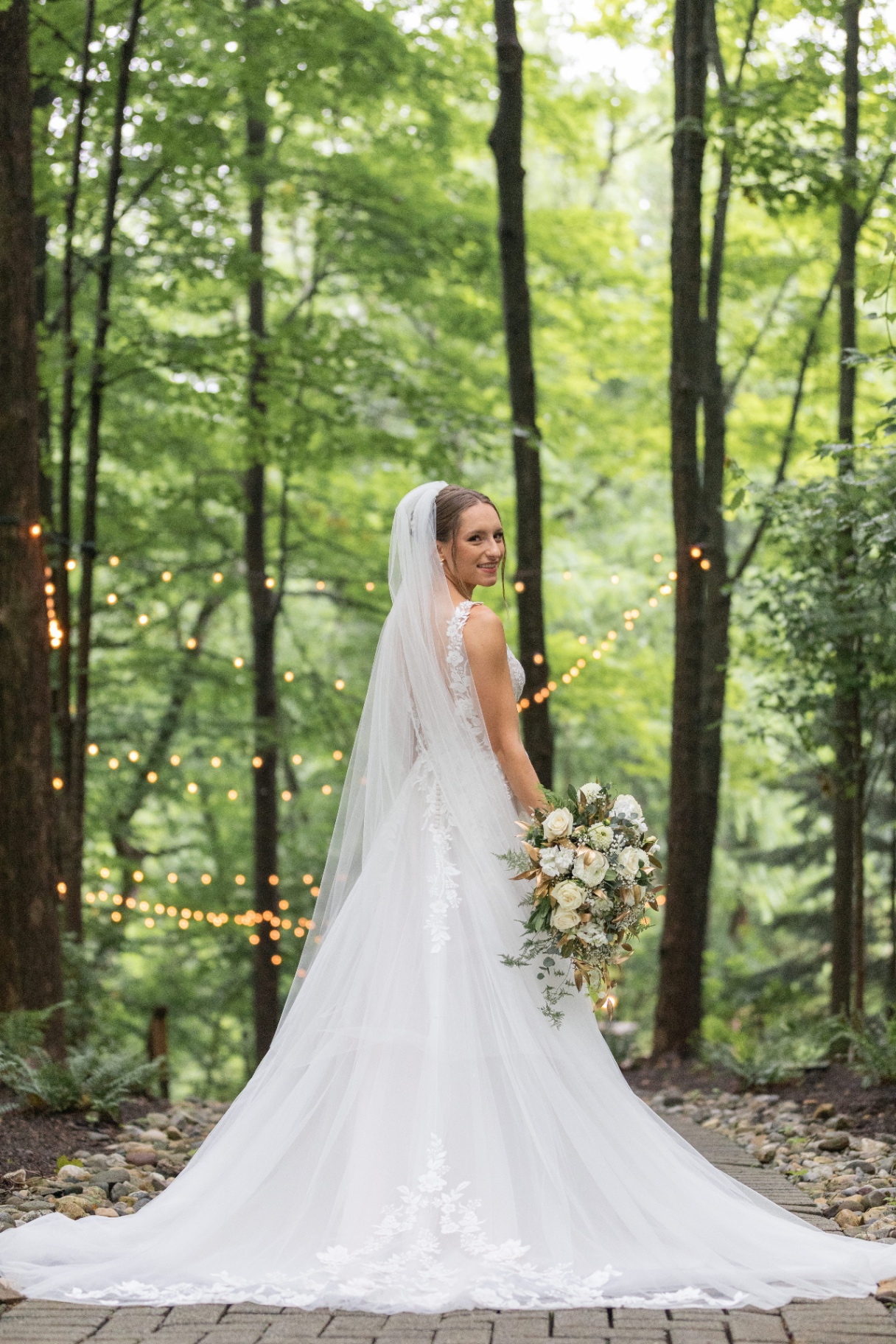 Bride in a lace wedding gown on wooded path