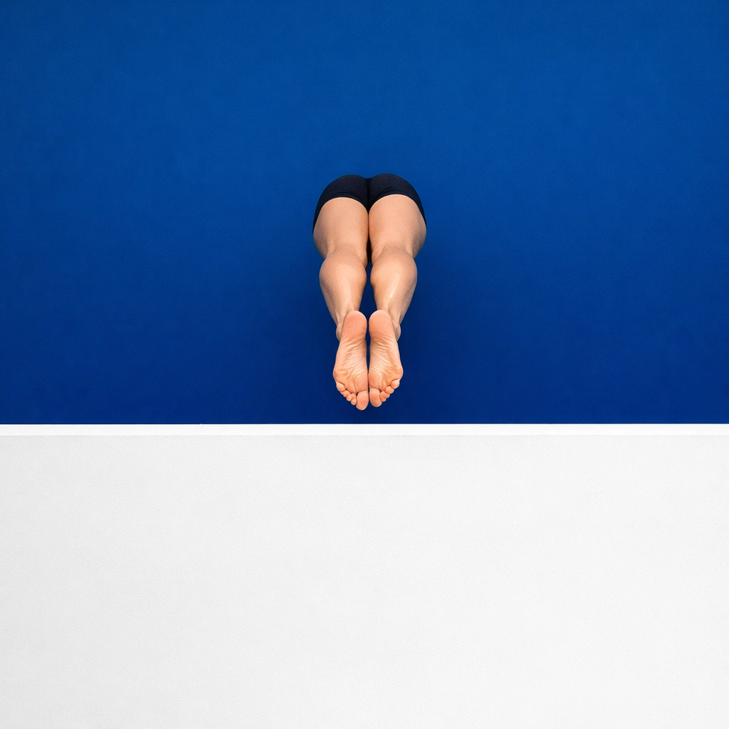 Swimmer pushing off a pool wall with pointed toes and fully extended legs for a streamlined glide.