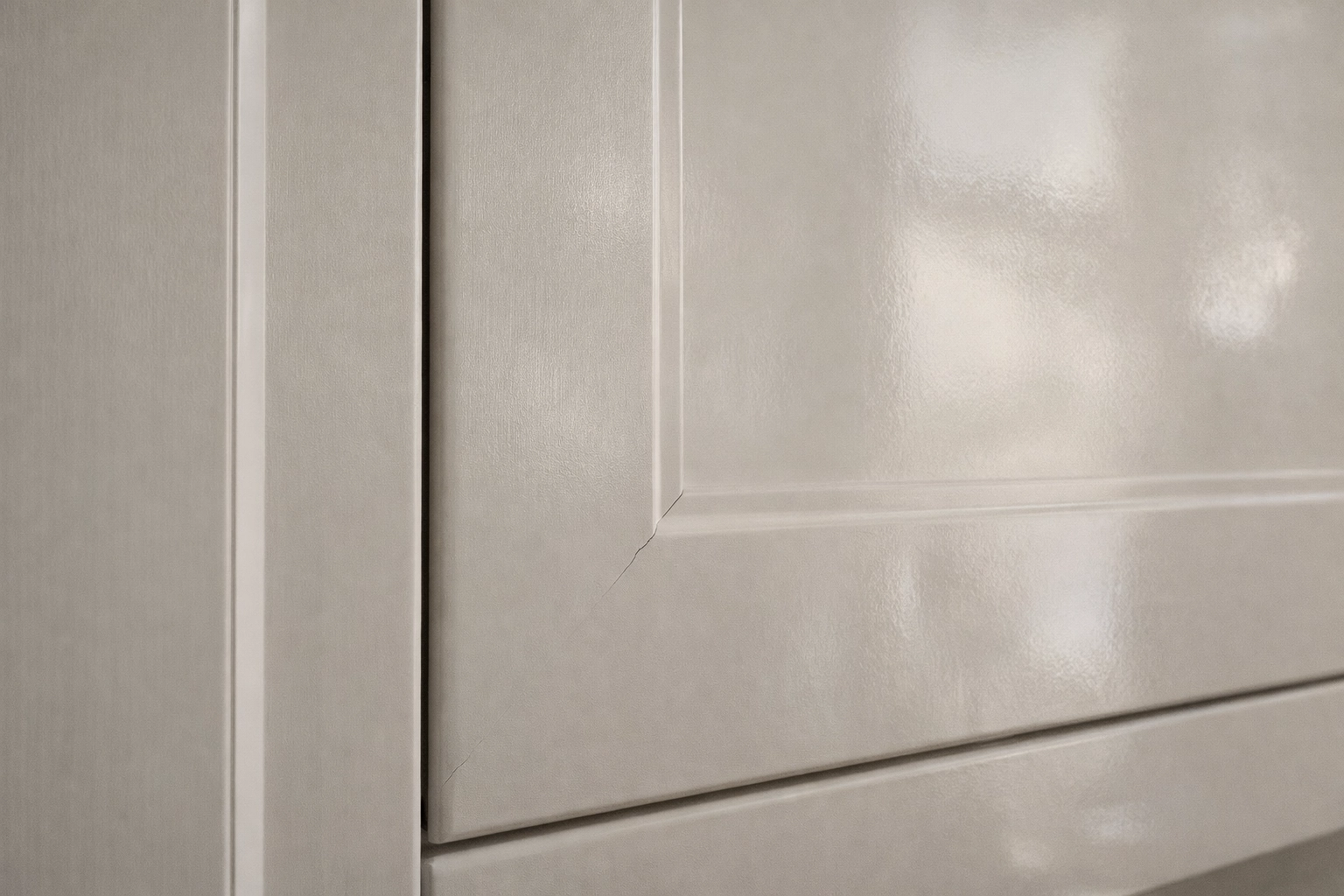 Close-up cabinet door detail showing seasonal movement: slight panel shrink gap, hairline crack at corner joint, and subtle finish distortion in soft natural light