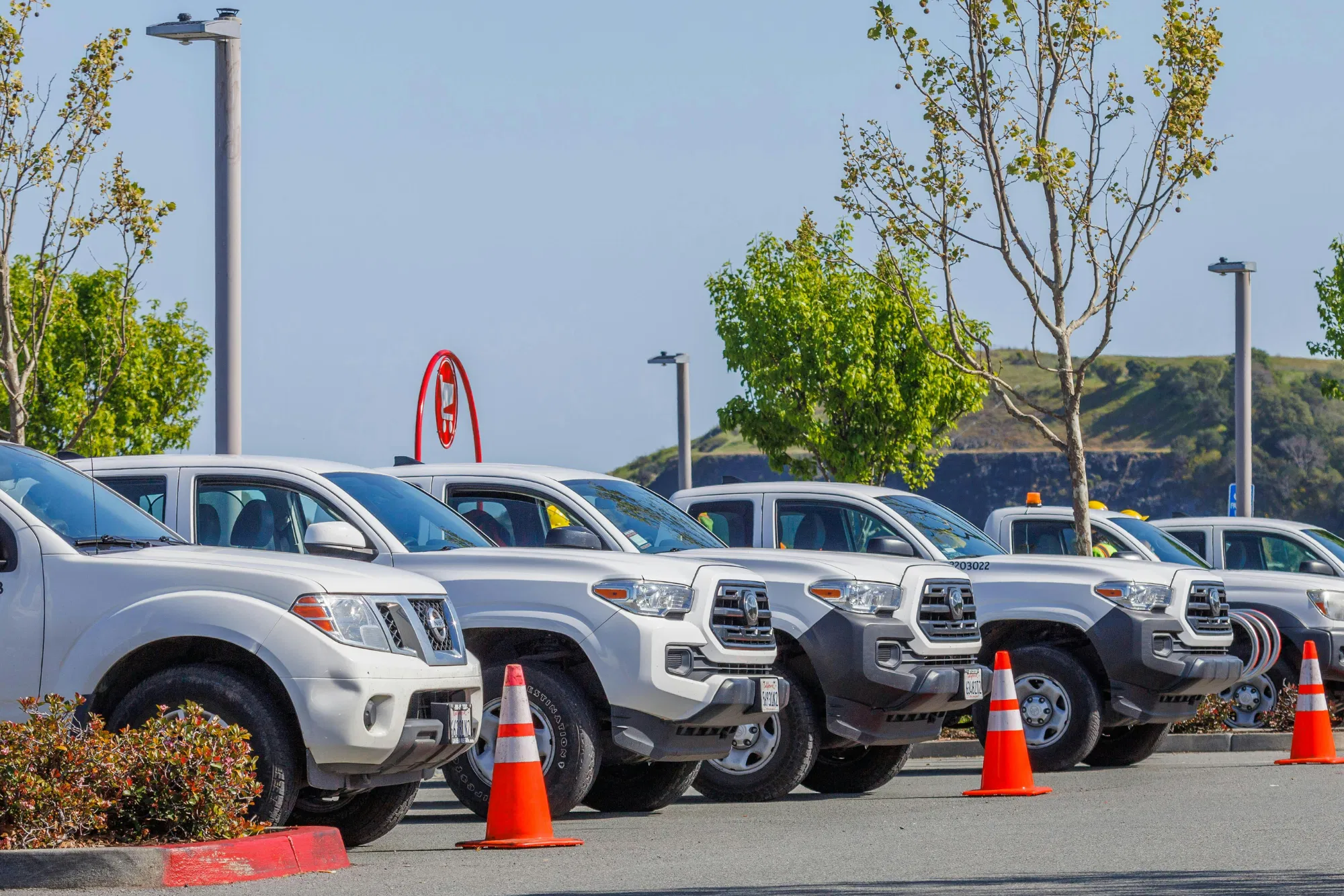 A row of white work trucks parked in a lot ready for dispatch for mobile maintenance