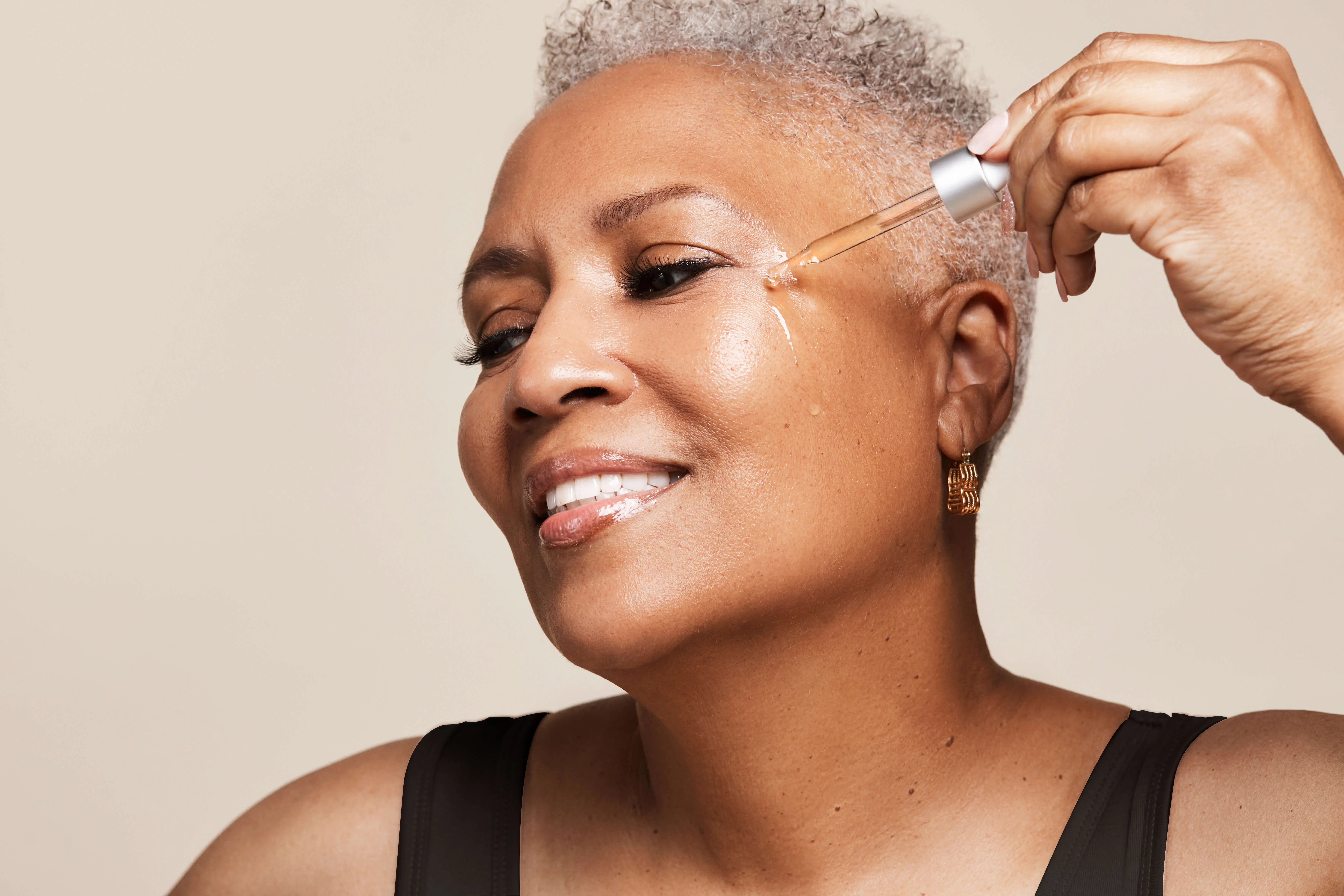 radiant-silver-haired-woman-applying-serum-face