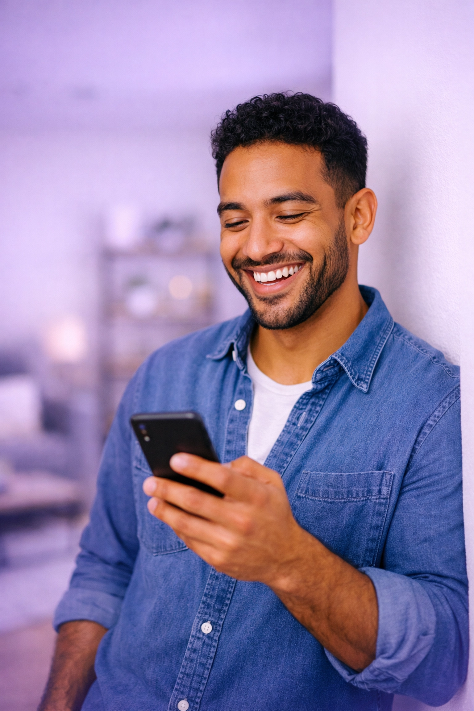 Smiling man relieved to find a bad credit loan in Canada using his smartphone in a modern apartment.