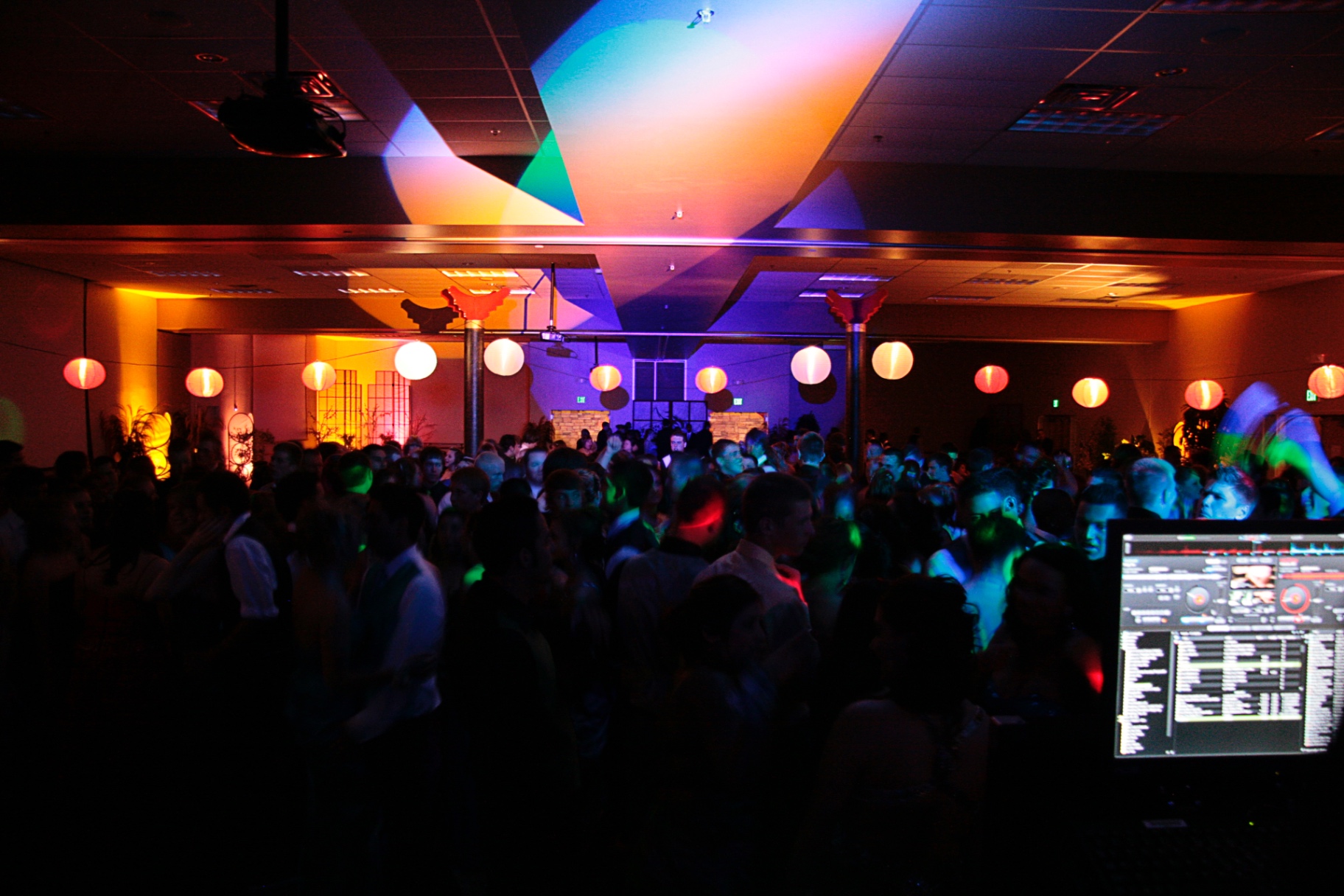 Packed Dance Floor with DJ Booth and Vibrant Lighting
