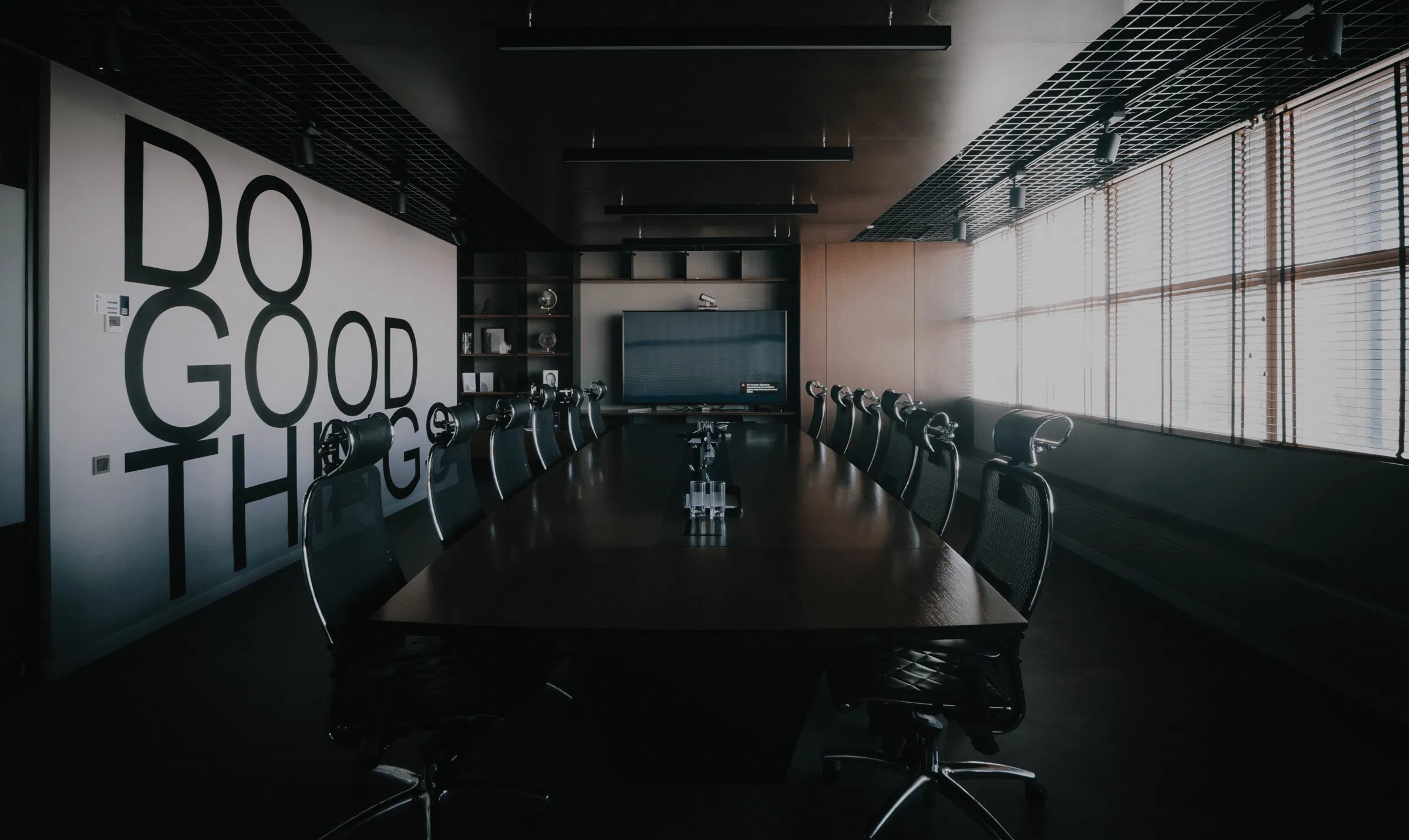 Modern corporate boardroom featuring a large wooden conference table and wall art