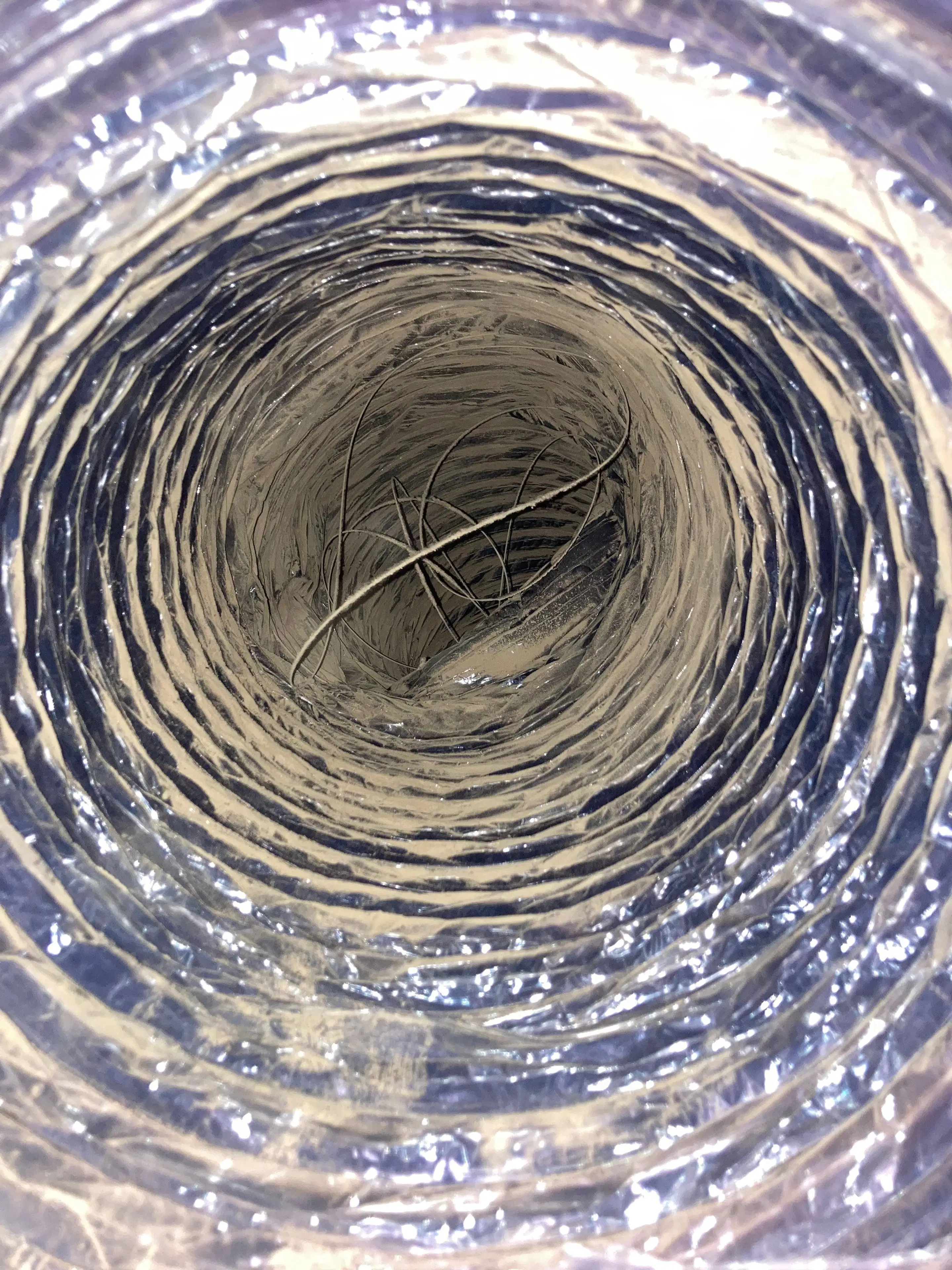 Interior view of a flexible air duct coated with a thick layer of dust and debris buildup