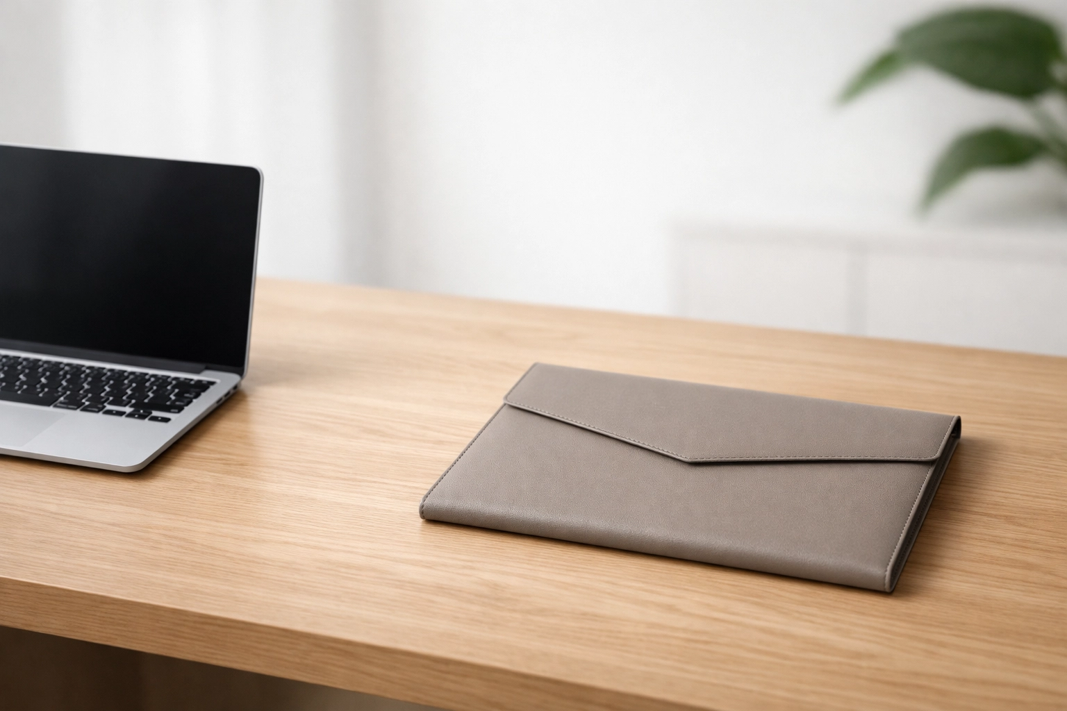 A clean minimalist desk with a laptop and document folio representing efficient ERO recordkeeping and tax business operations.