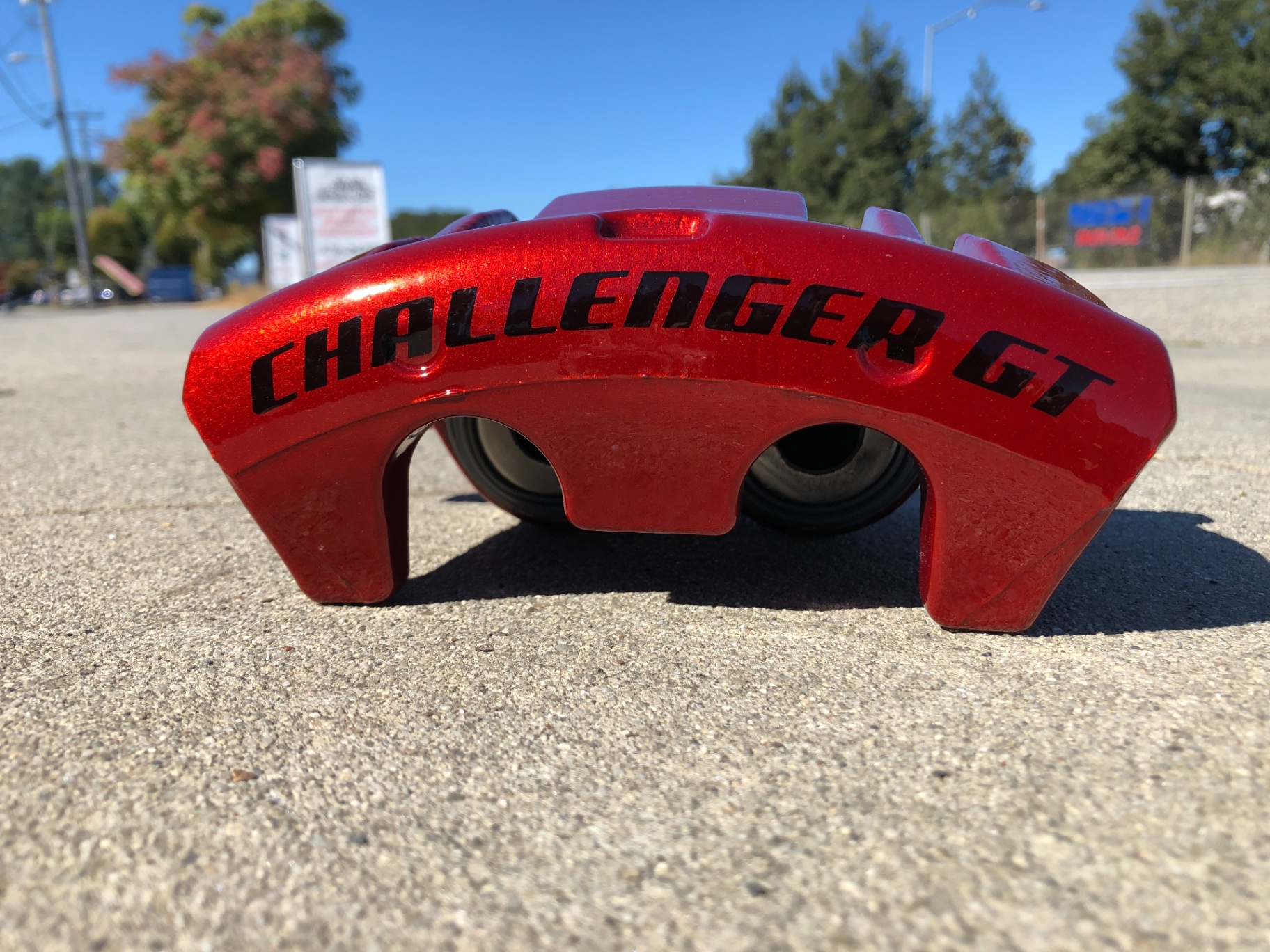 Custom Powder Coated Red Dodge Challenger GT Brake Caliper A custom powder coated red Dodge Challenger GT brake caliper with a gloss finish and bold black 'CHALLENGER GT' model decal, showcased outdoors in natural light to emphasize the quality and depth of the powder coating.