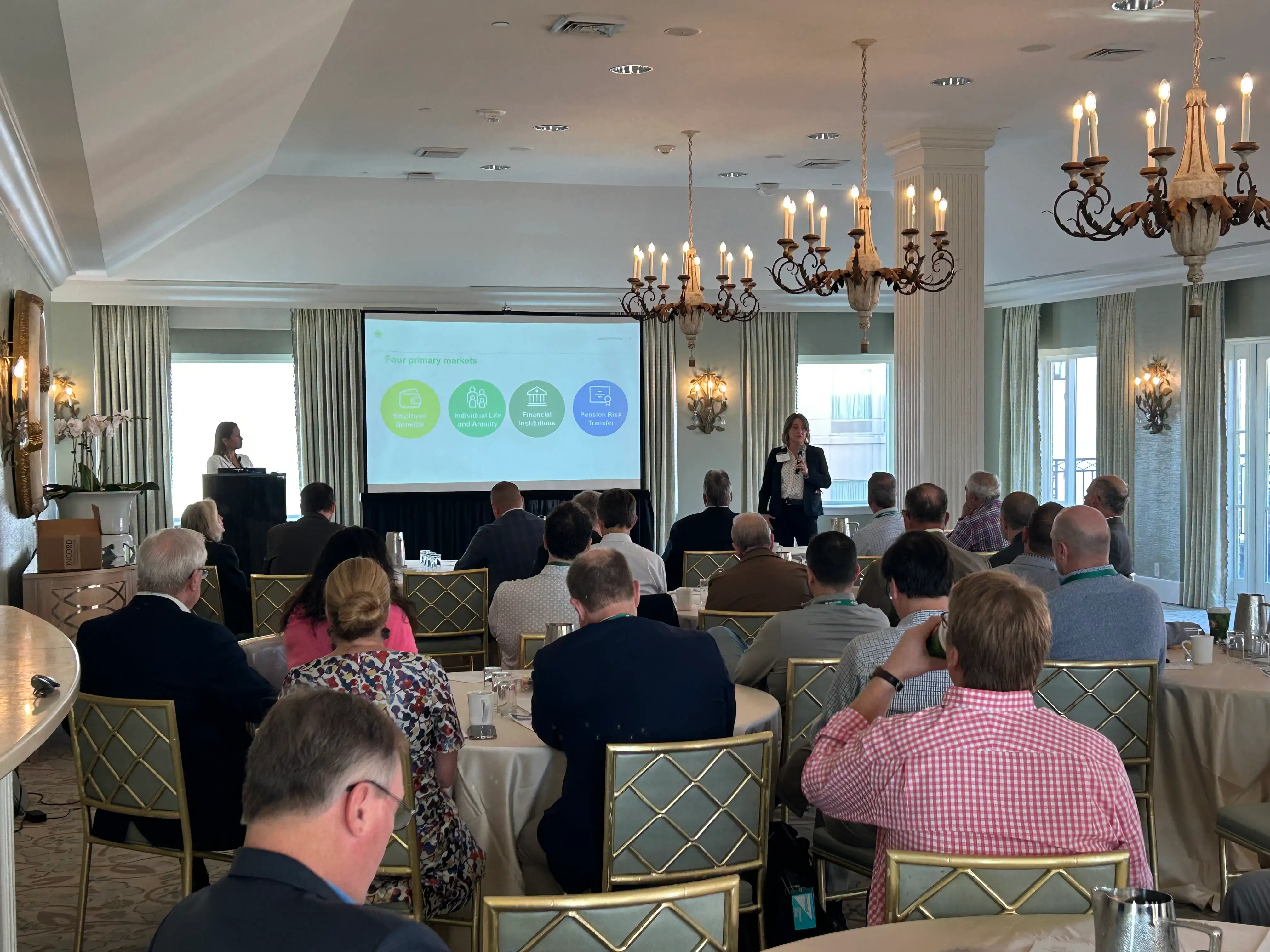 Business professionals at a conference discussing strategy and executive benefits