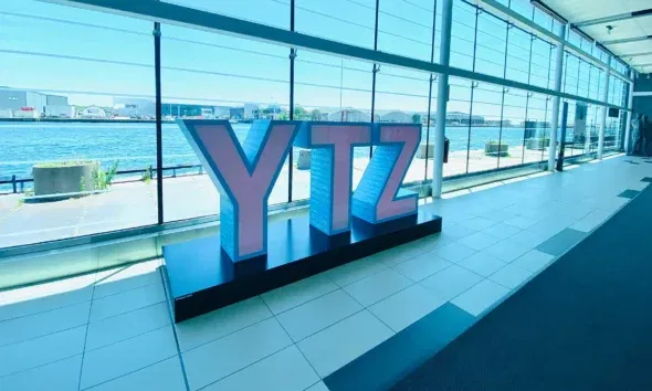 Large YTZ letters stand inside the glass-walled terminal at Billy Bishop Toronto City Airport, highlighting Toronto’s vital role as a Canadian travel gateway and infrastructure hub.