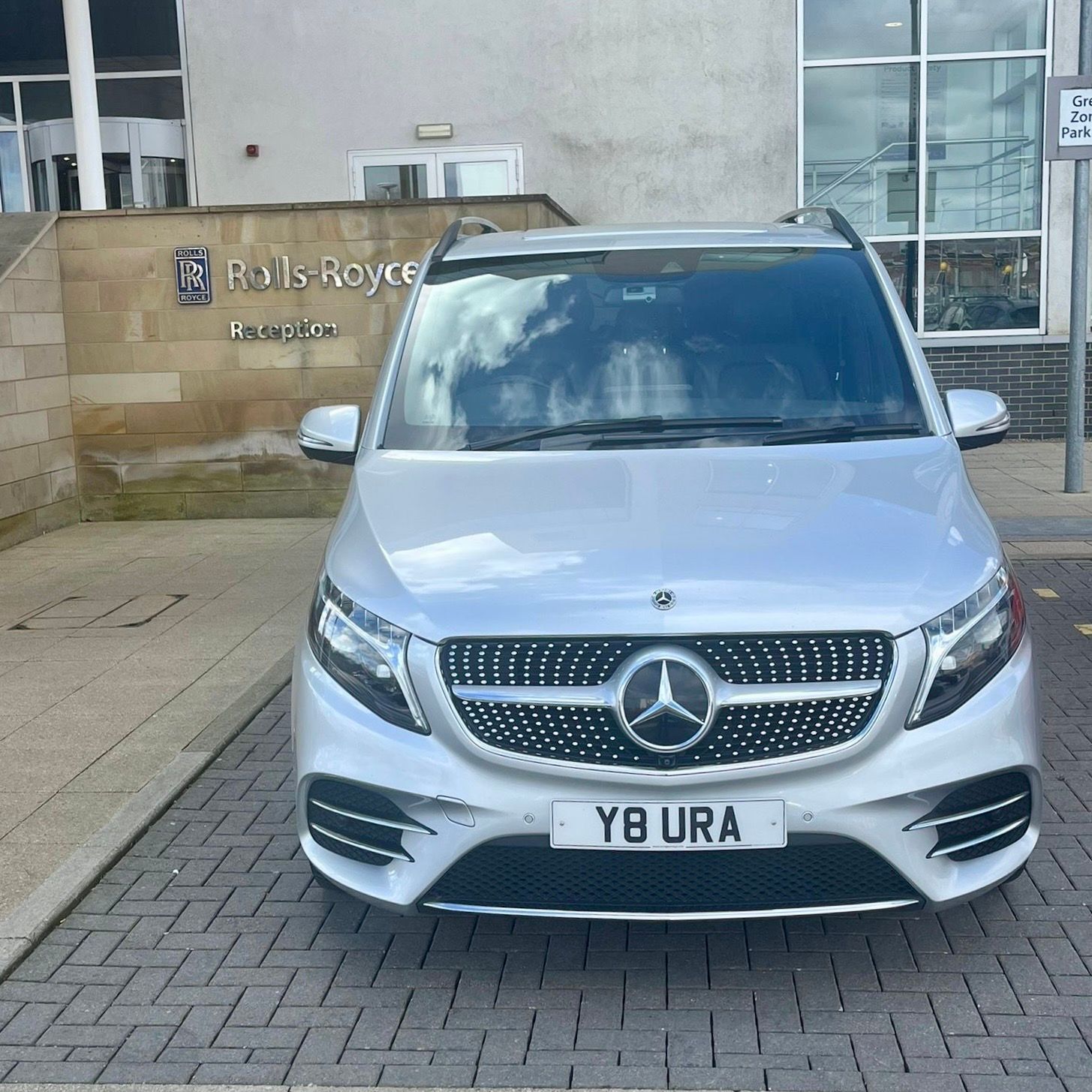 A silver Mercedes-Benz V-Class with Aura Journeys branding parked at an executive reception