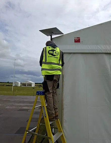 Commsuk technician installing a satellite dish for event connectivity