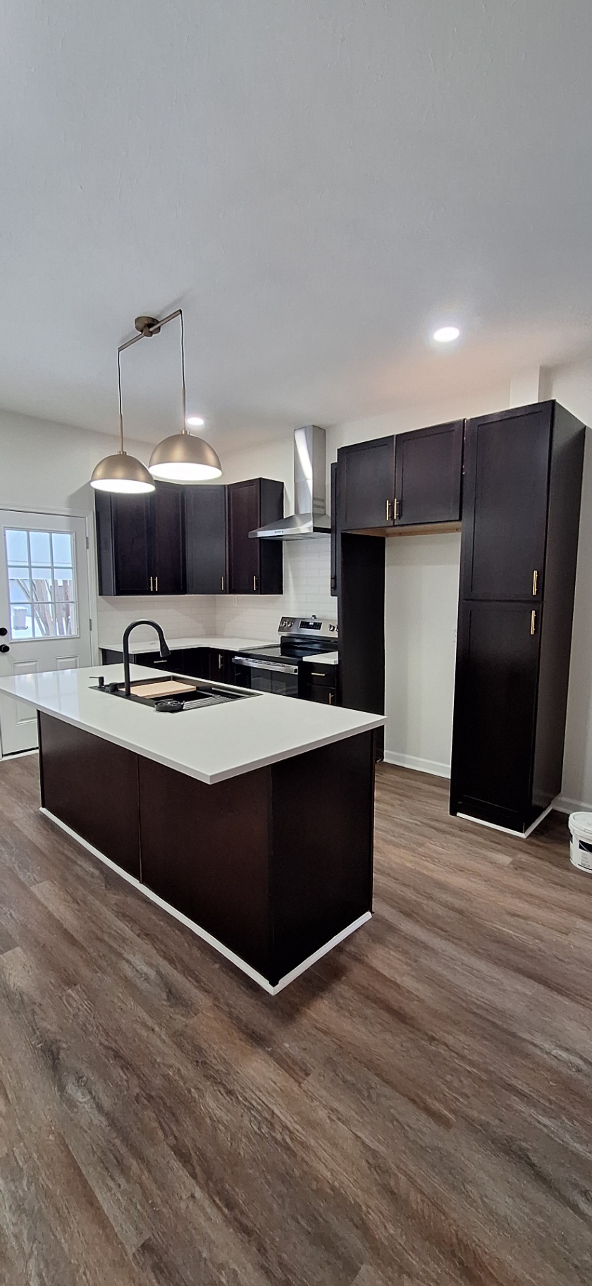 Kitchen features new dark wood cabinets, modern white countertops, and fresh paint