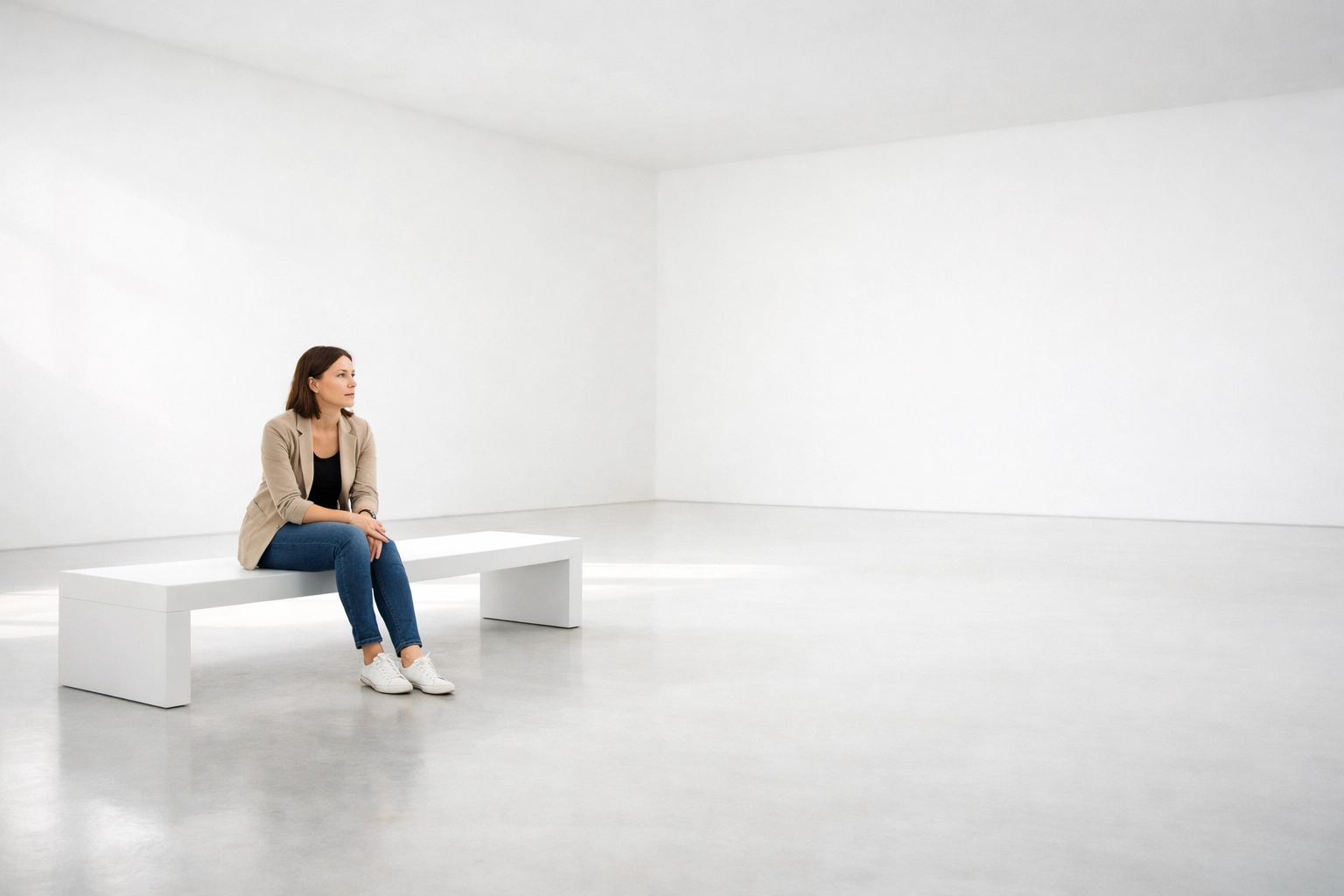 Woman sitting alone on a white bench, illustrating the feeling of loneliness and social disconnection.