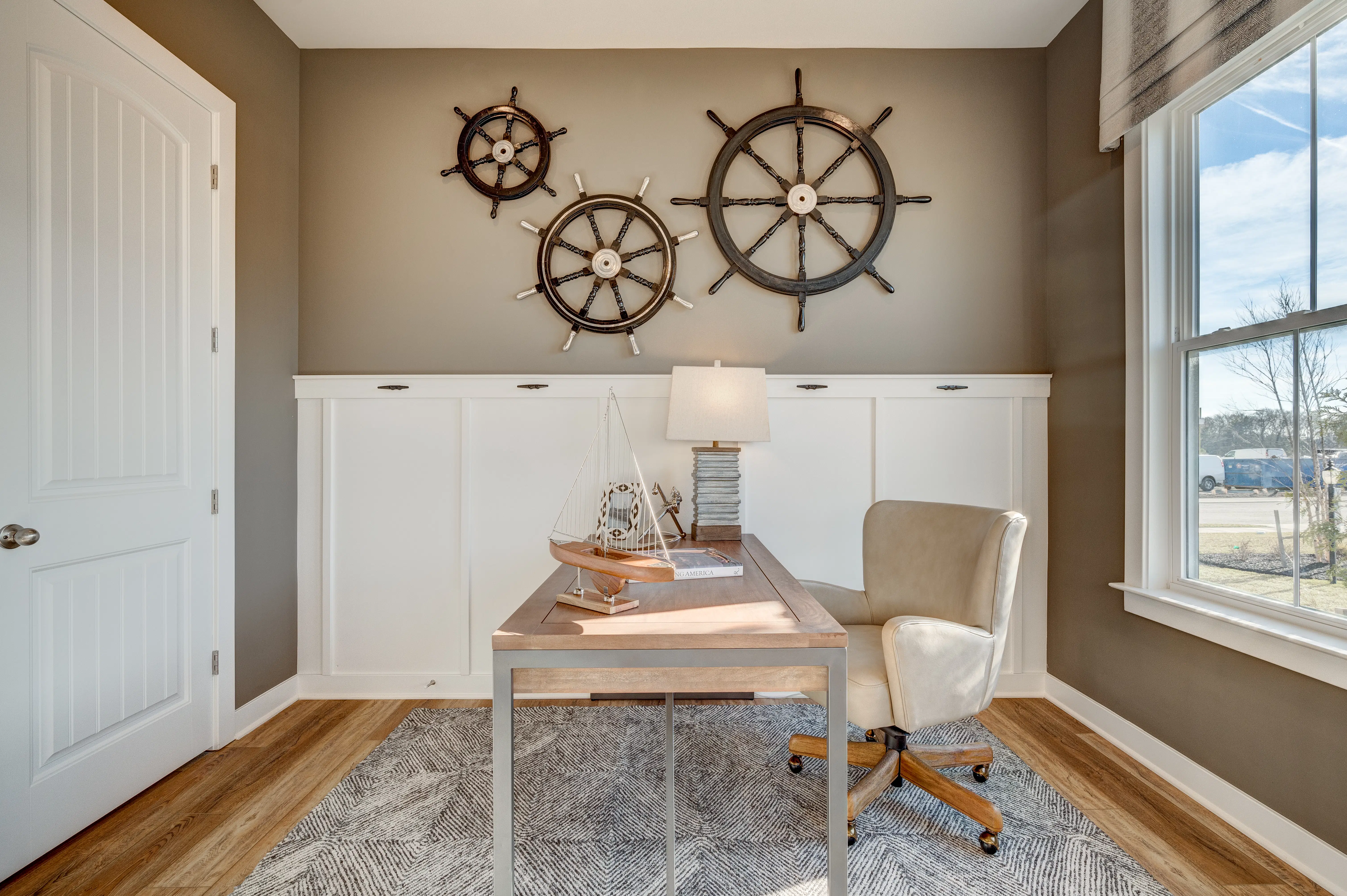 Bright home office featuring nautical décor with ship wheels and a modern desk setup