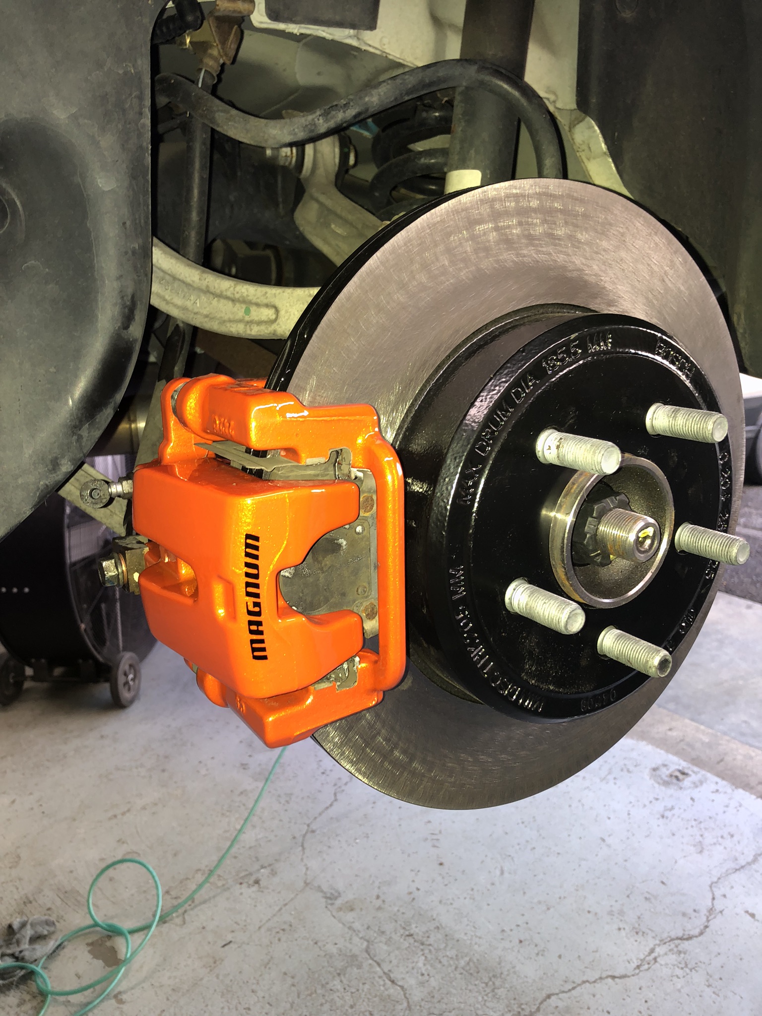 Bright orange powder coated Dodge Magnum caliper behind a wheel (real customer photo)