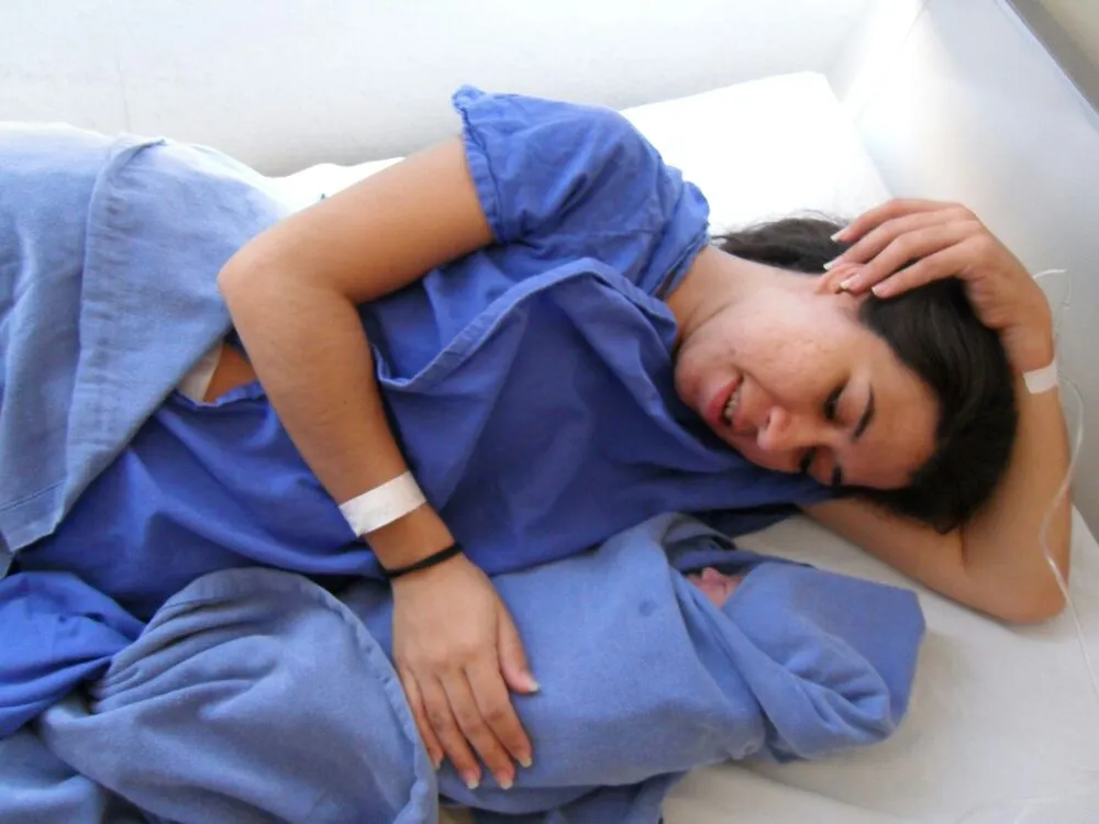 Aura en el hospital en contacto piel con piel con su bebé, reflejando el inicio real de la maternidad.