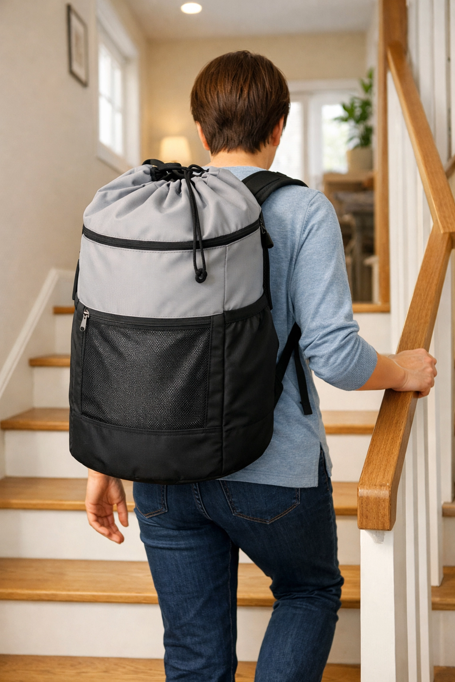 A person using a laundry backpack and a sturdy handrail to safely climb stairs with both hands free.
