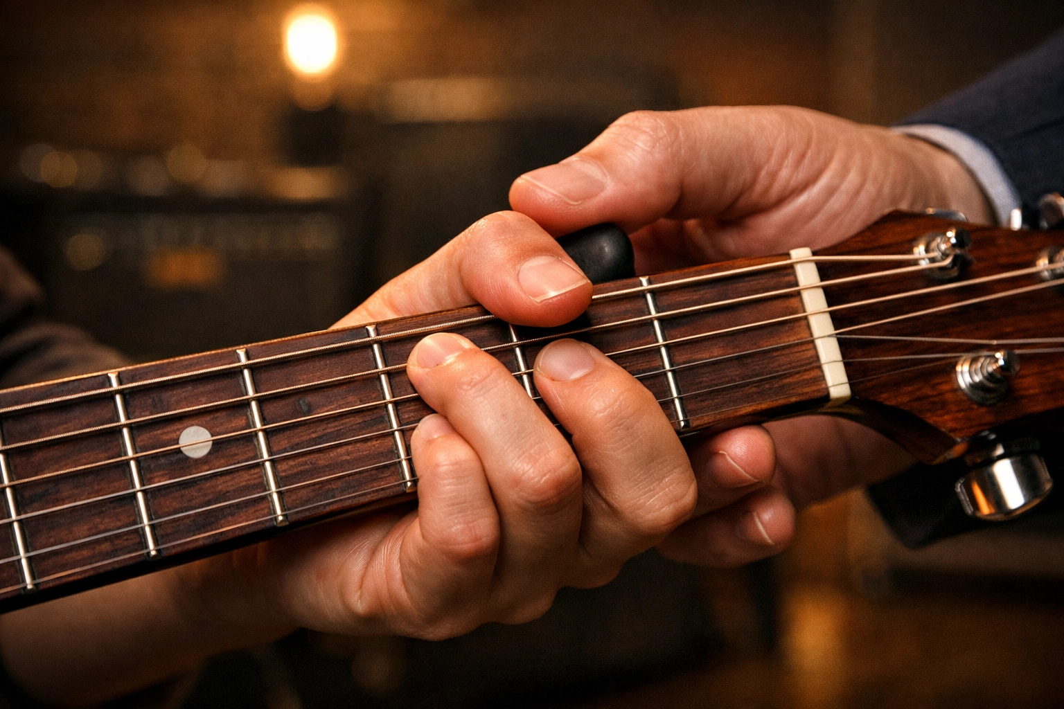A guitar teacher in Tallahassee corrects a student's hand positioning on a fretboard during a lesson.