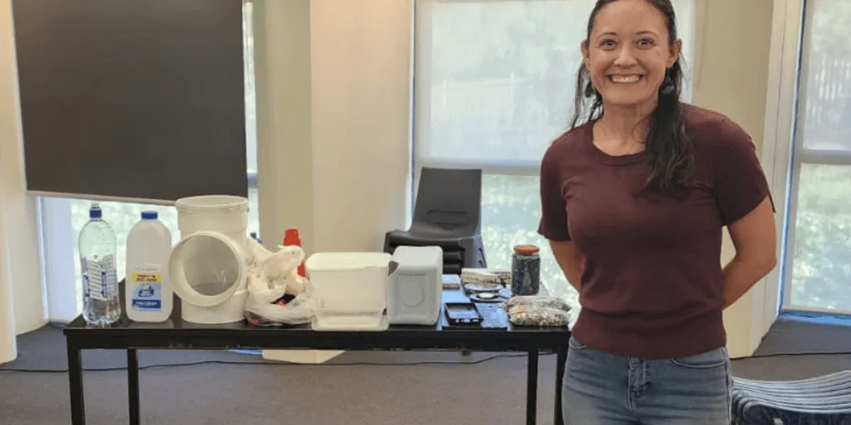 Resourceful Living team member beside a table displaying various types of collected plastic waste