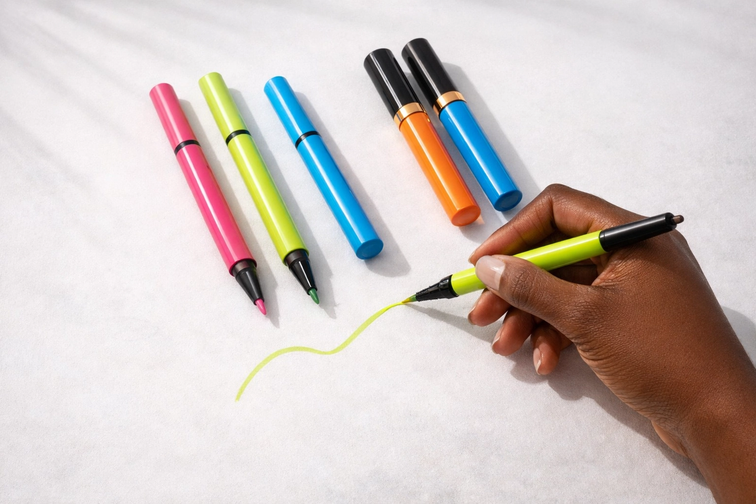 Ashunta Inc UV Neon collection liners and mascaras product shot with brown hand holding a neon liner