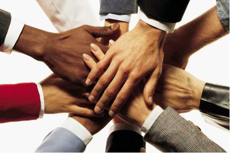 Team Collaboration Hands Multiple hands from diverse team members overlapping in the center, symbolizing collaboration, unity, and collective commitment.