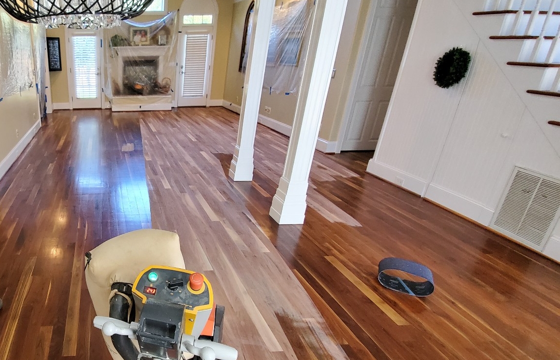 Ongoing hardwood floor refinishing project showing the transition between old and new surfaces