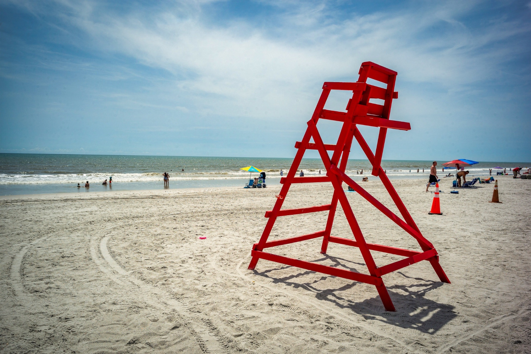 Wide-angle beach scene with red lifeguard stand