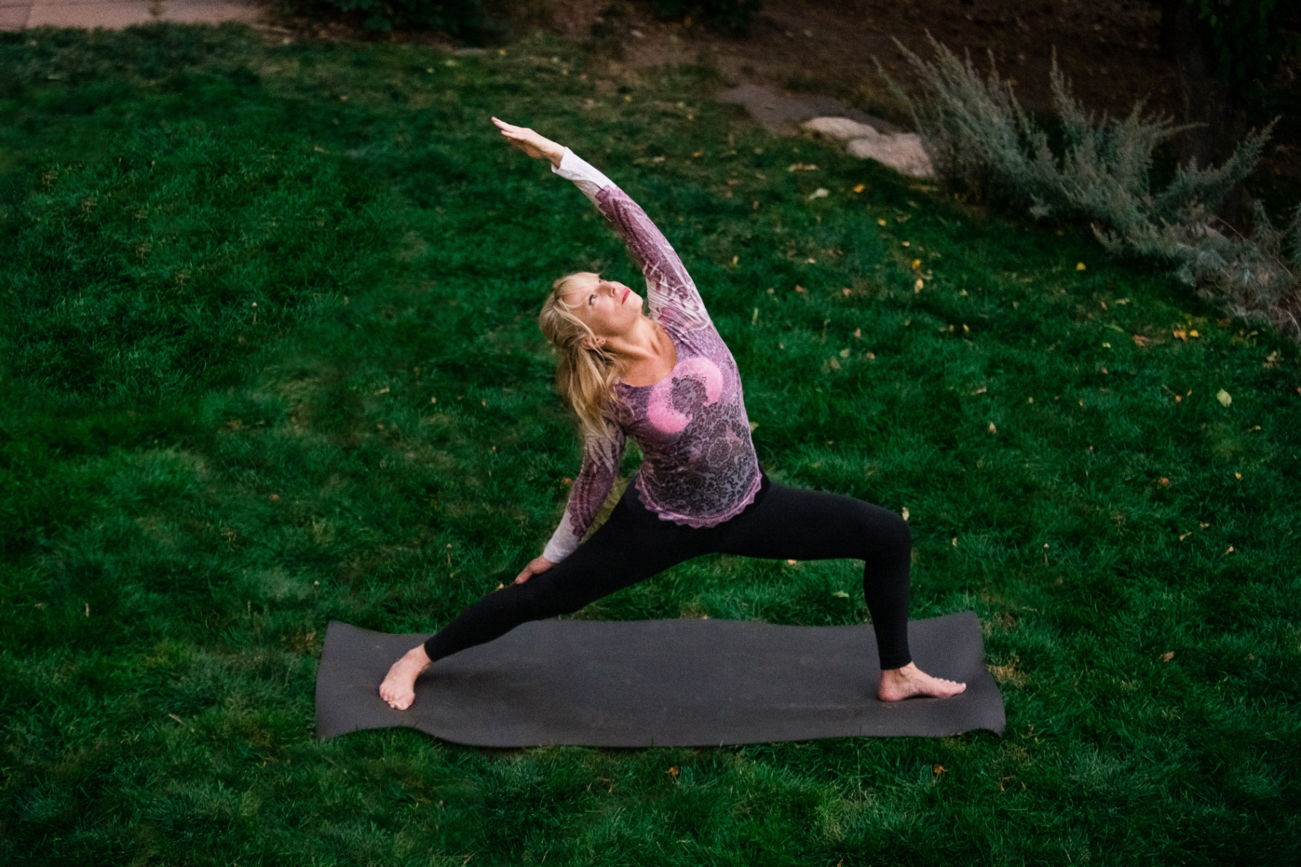 Woman Practicing Yoga Outdoors A woman practices yoga outdoors on a mat, demonstrating work-life balance and wellness, values supported by Castle Rock Investment Company's retirement solutions that help businesses provide holistic benefits for their employees.