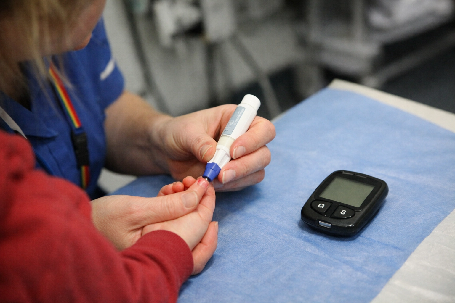 A paediatric nurse performs a finger-prick blood glucose test on a toddler to screen for Type 1 diabetes.
