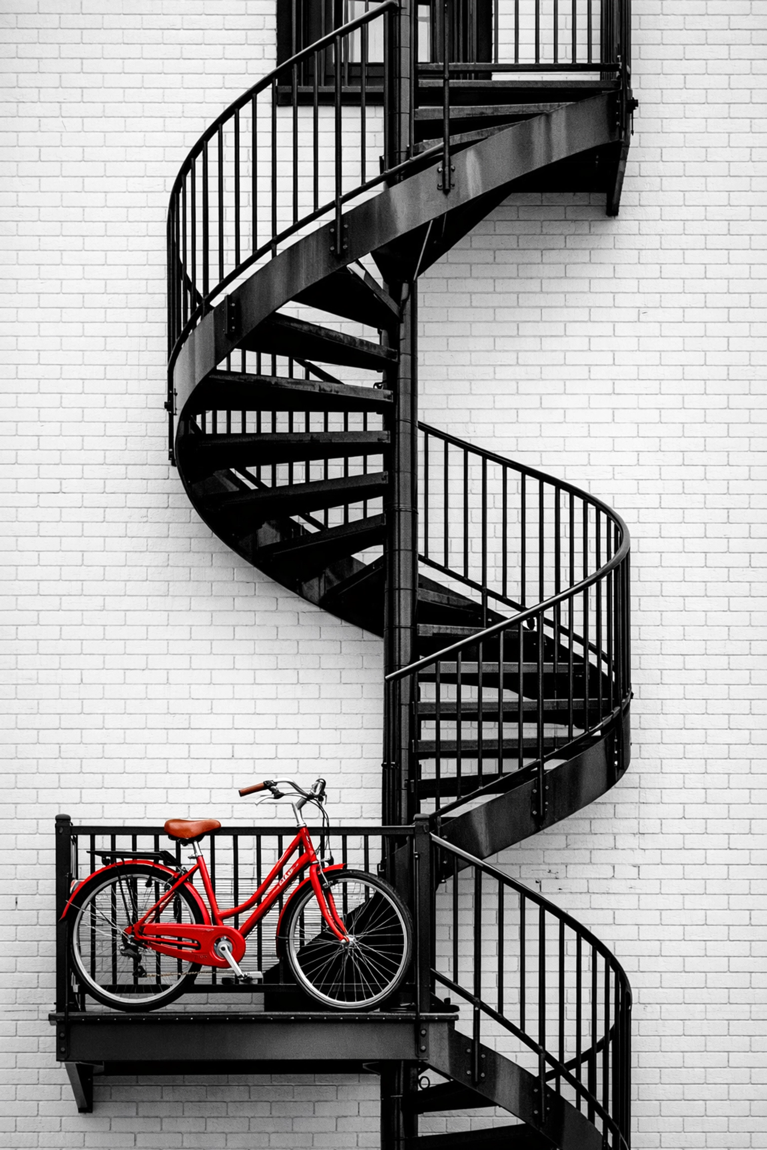 Escalier en colimaçon emblématique du quartier Limoilou avec un vélo de ville rouge.