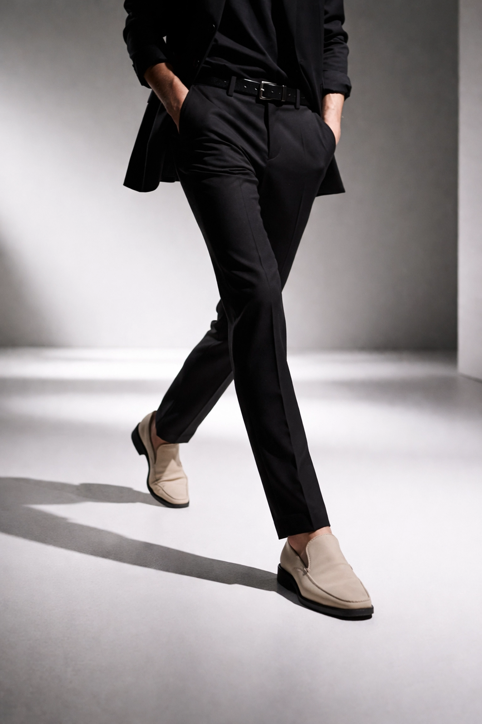 Male model in stylish black runway attire and classic shoes walking confidently, emphasizing proper dress code for modeling auditions.