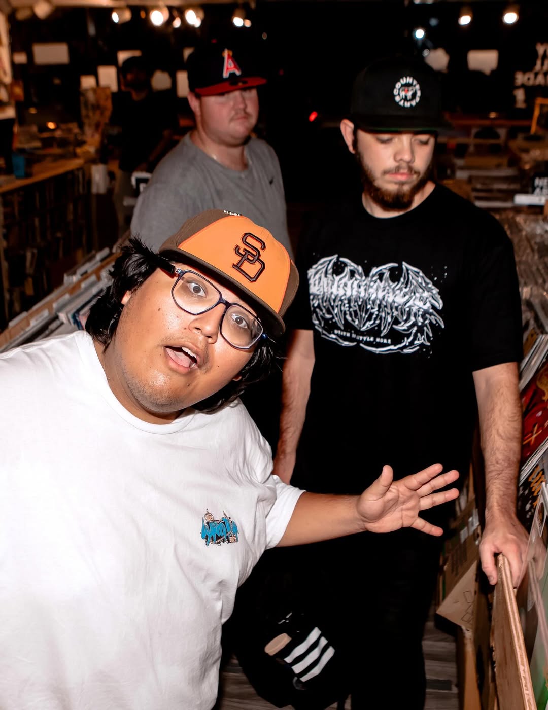 Three customers browsing through rows of vinyl records inside the Nivessa store