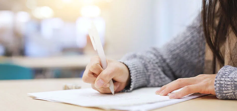 A woman in a cozy sweater sits at a desk, filling out psychological assessment forms