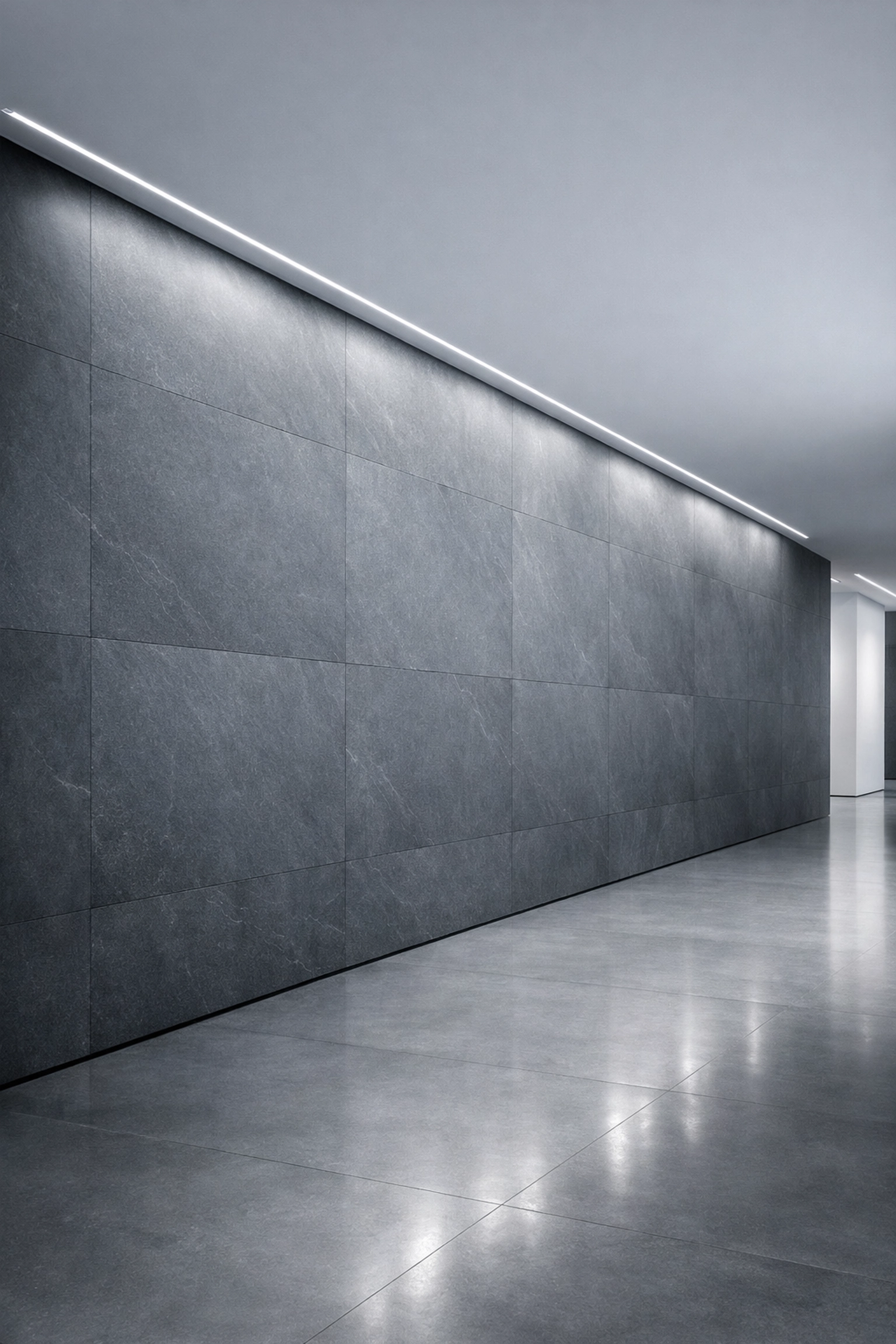 Seamless large format slate-grey stone slabs from the Stratos Collection in a modern hallway.