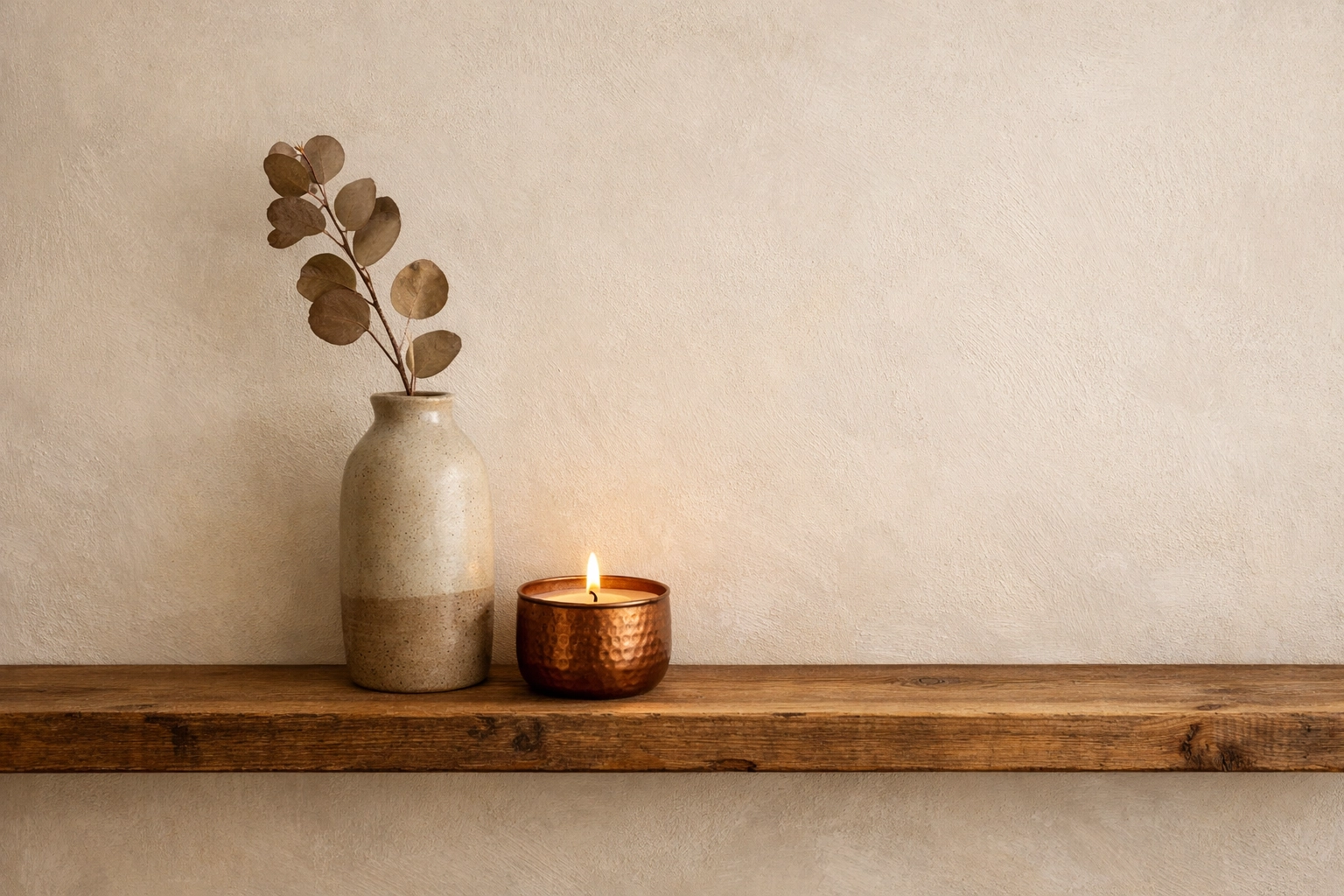Minimalist wooden shelf with a handcrafted stoneware vase and candle reflecting curated home decor.
