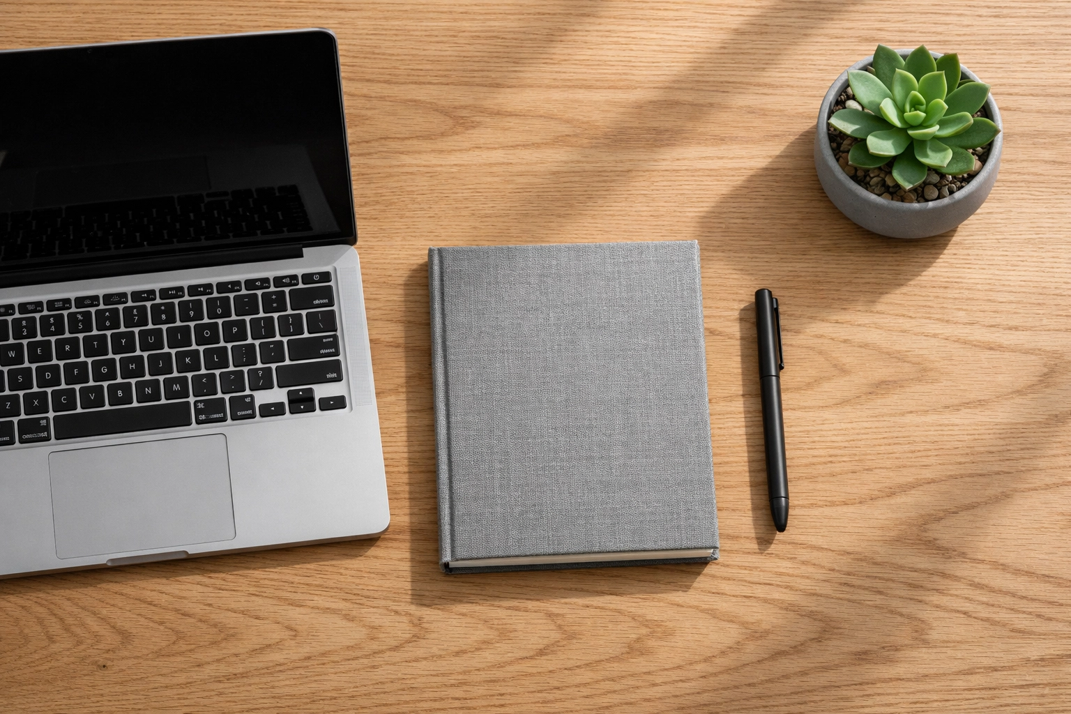 Minimalist desk with a laptop and notebook, symbolizing a streamlined business process and organized workflow.