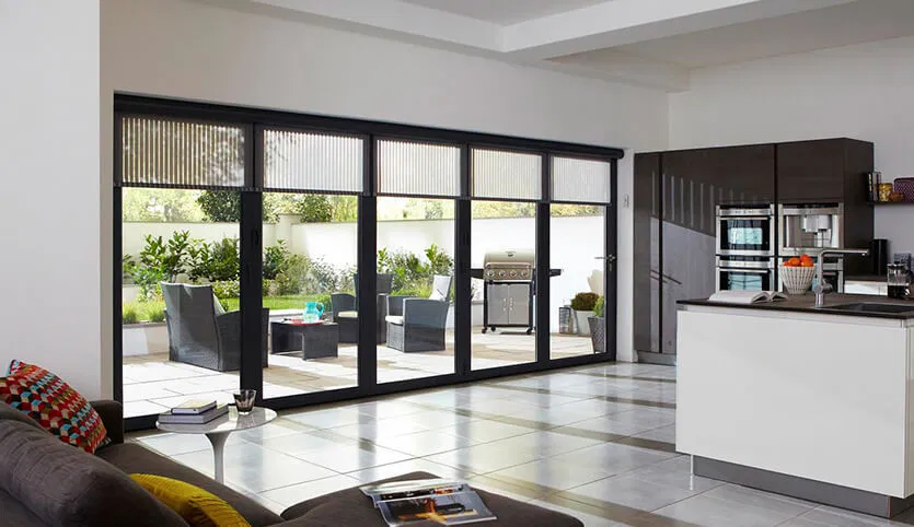 Large, black-framed bifold doors span the width of a contemporary open-plan kitchen and living area.