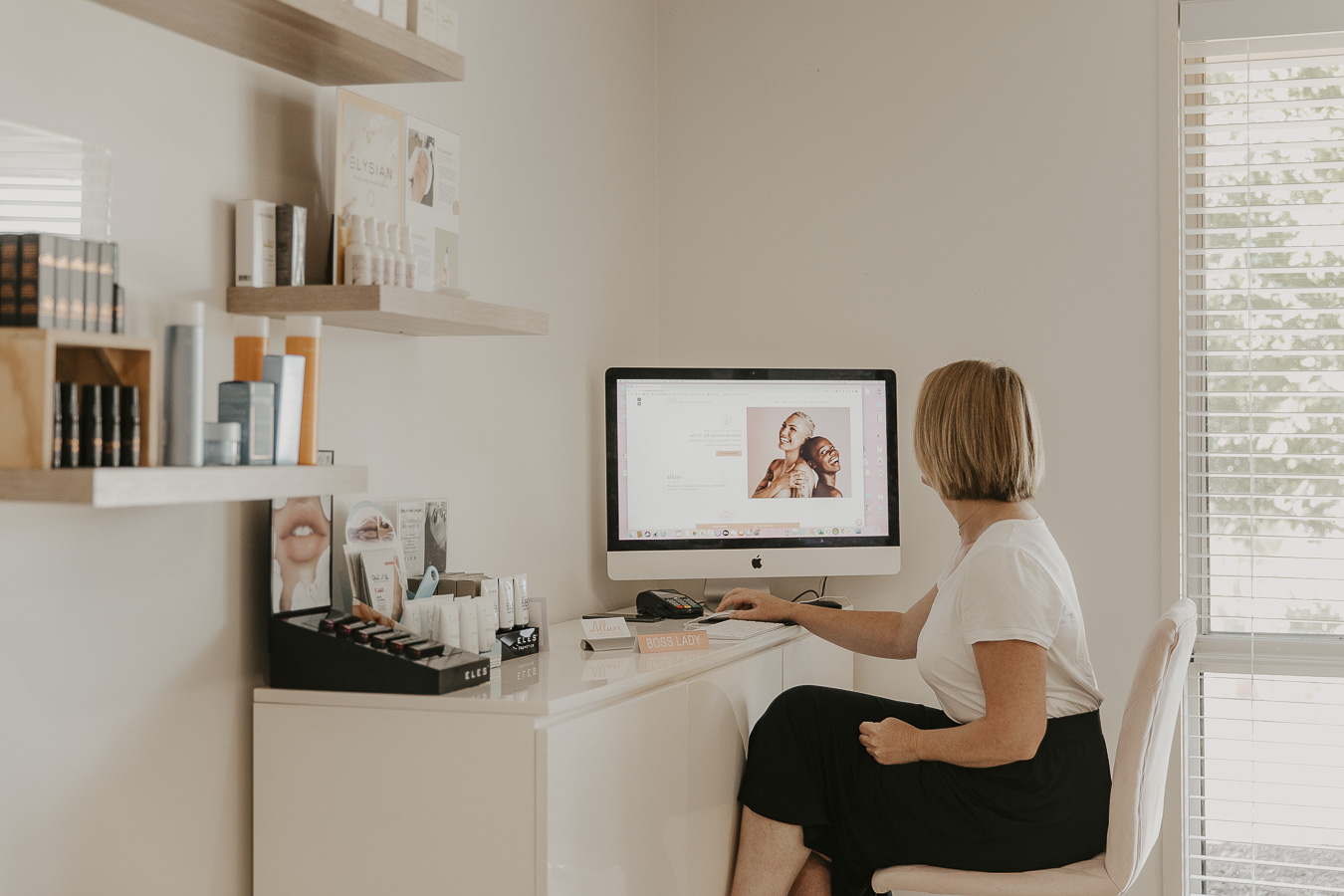 A staff member is seated at a white desk in a bright, welcoming consultation area
