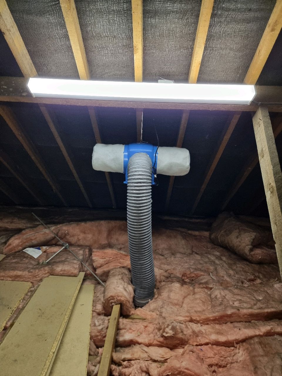 Positive Input Ventilation (PIV) System Installation A PIV system installed in a residential loft space, featuring insulated ducting to help reduce mould, damp, and condensation. The area includes loft insulation and a newly fitted LED ceiling light to improve visibility during installation and maintenance.