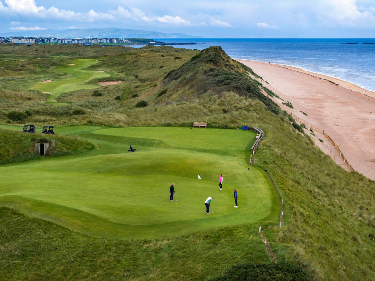Aerial view of championship links golf course on Northern Ireland coastline with dramatic cliffs