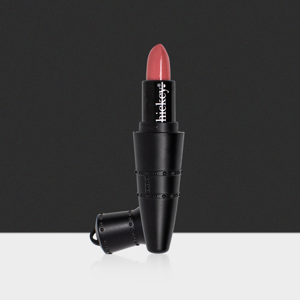 Hickey Lipstick Refillable pendant-style lipstick case in matte black with rivet detailing, featuring a warm rose shade. Boldly pigmented, creamy, and organic lipstick designed for long-wearing hydration and UV protection; doubles as a fashionable accessory.