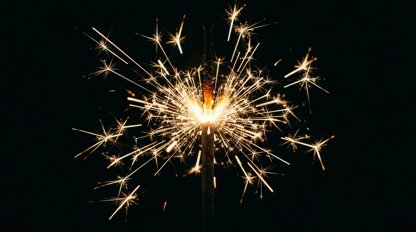 A single sparkler burning in a deep black void, chaotic golden light