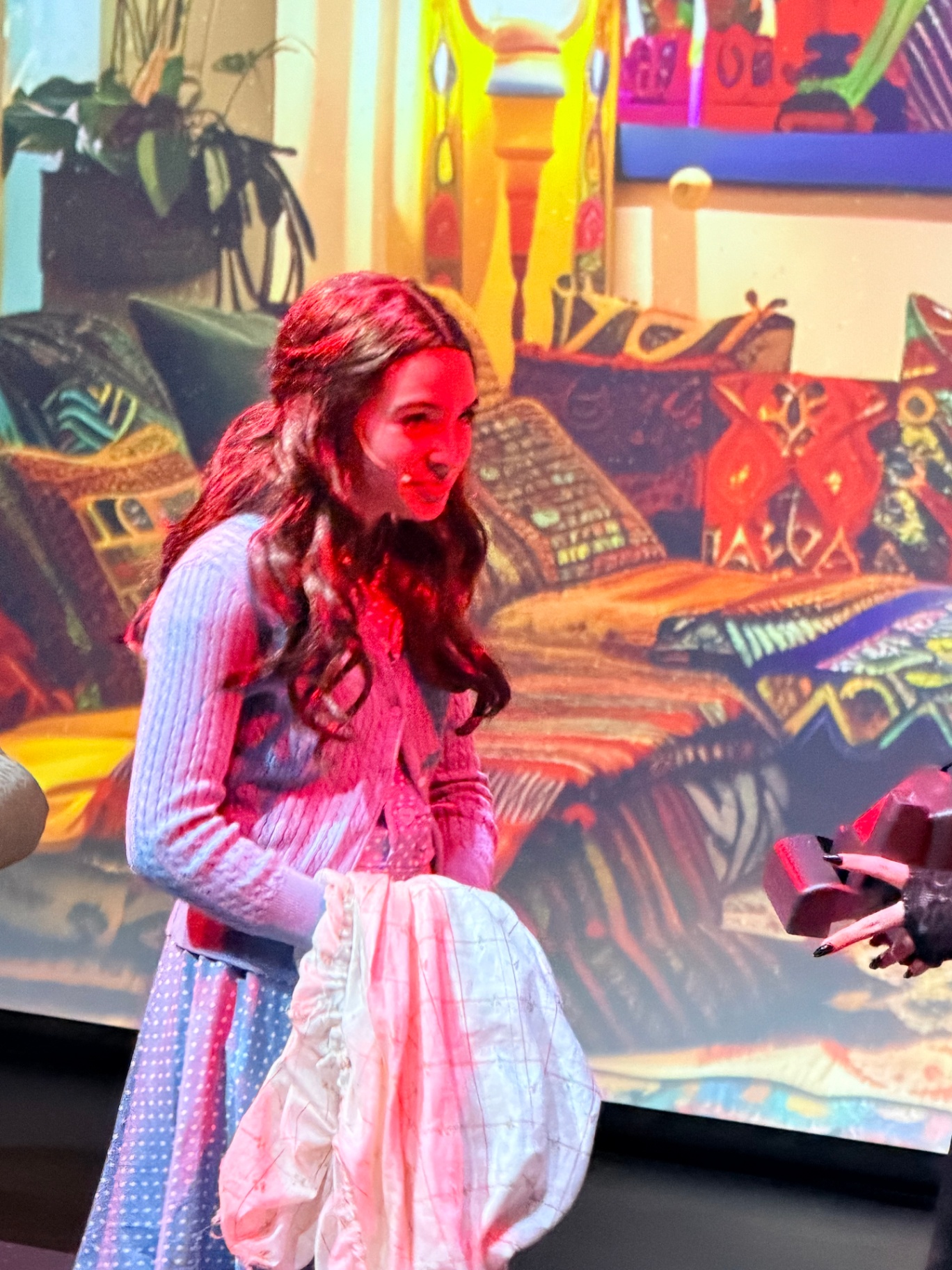 Rockwall Acting Theater Student Performance A young student in costume performs on stage during a Rockwall Acting theater production, holding a prop and interacting with another actor. The colorful, detailed set and expressive acting showcase skills acquired in acting and musical theater classes.