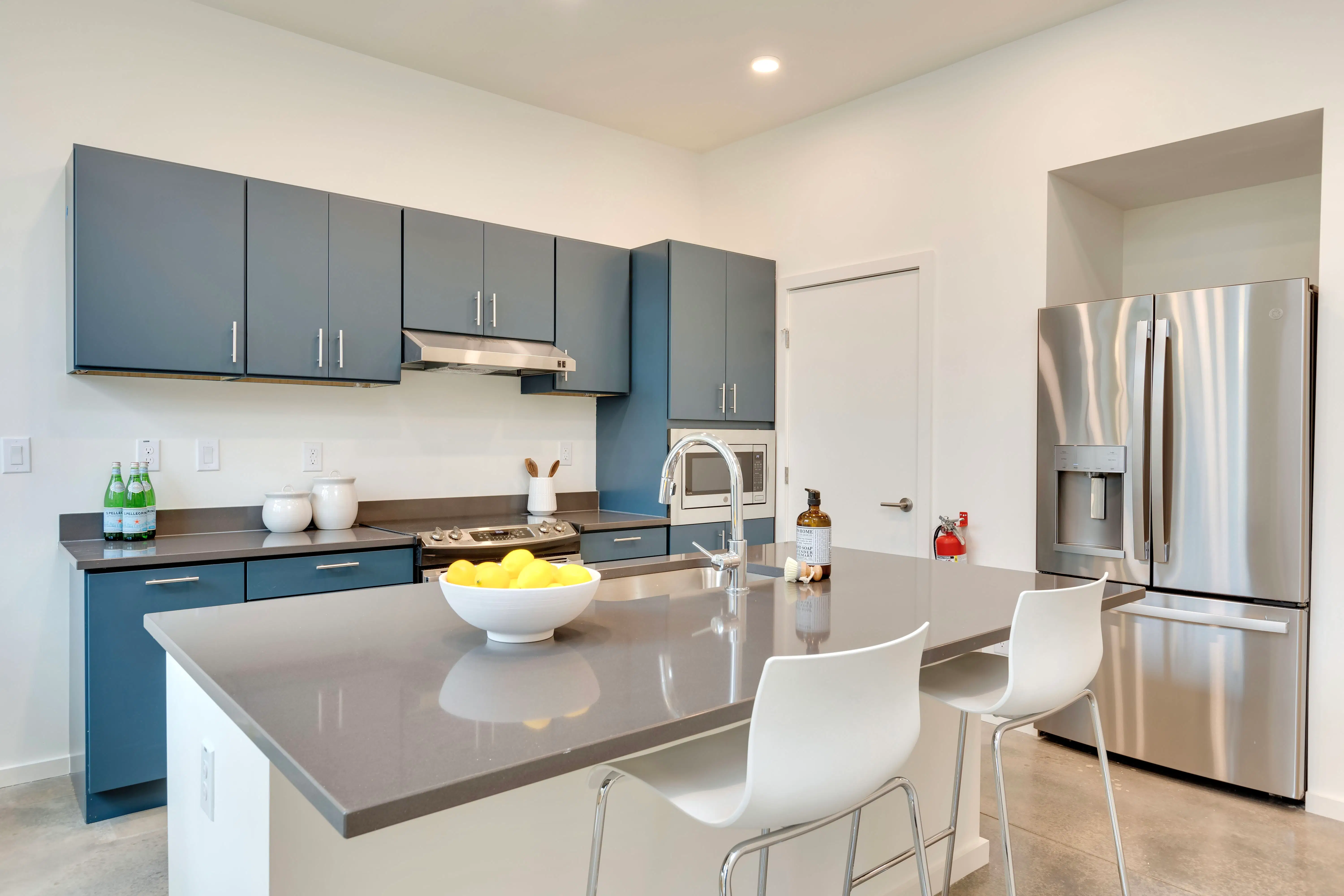 Modern community kitchen featuring sleek grey countertops and blue cabinetry
