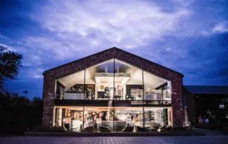 The Colony Group Wilmslow dedicated Glass Barn exterior at dusk — a modern Cheshire wedding venue with a warm, evening glow.