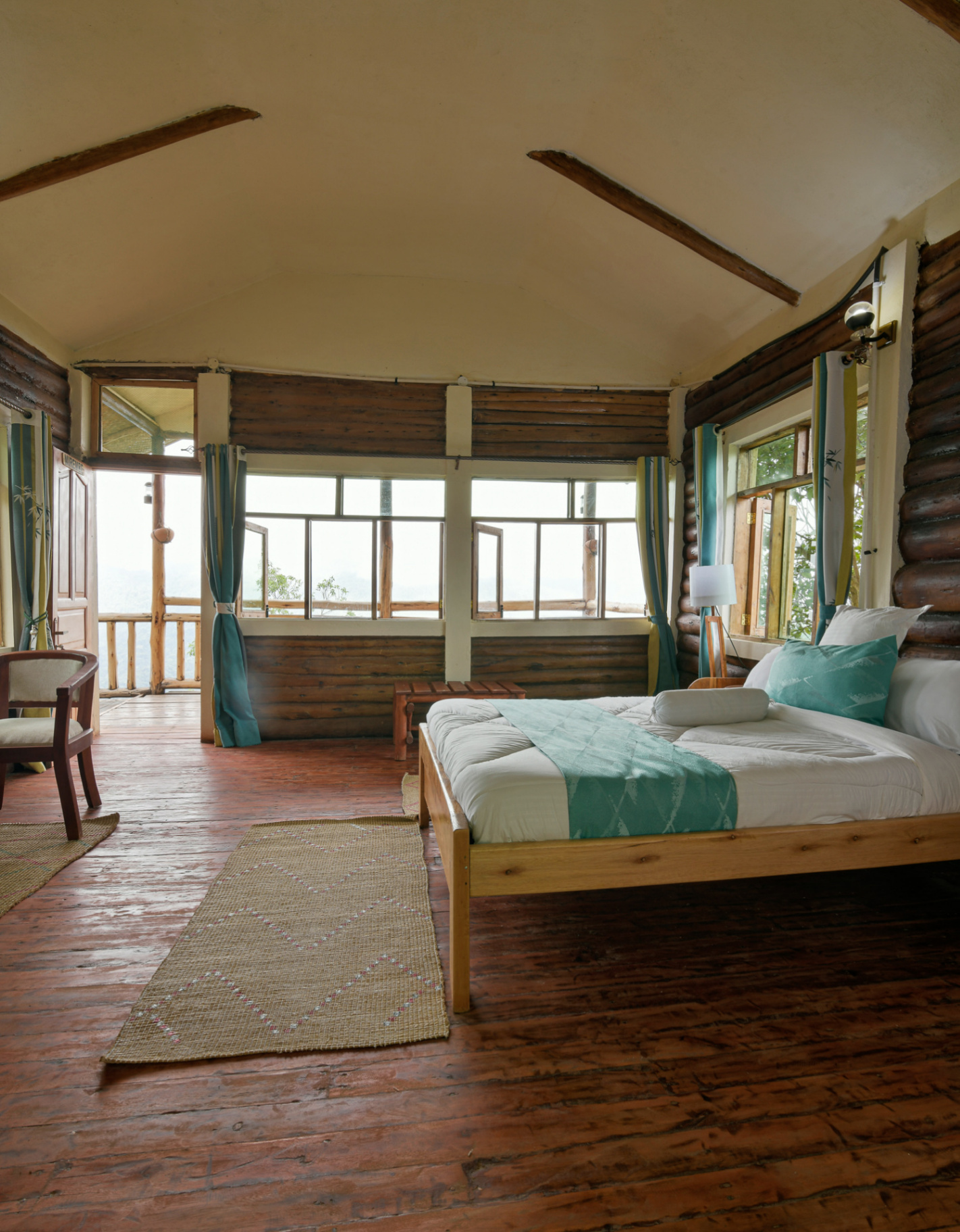 Orugano Bwindi Lodge guest room with turquoise accents, handmade mats, and private balcony overlooking Bwindi Forest